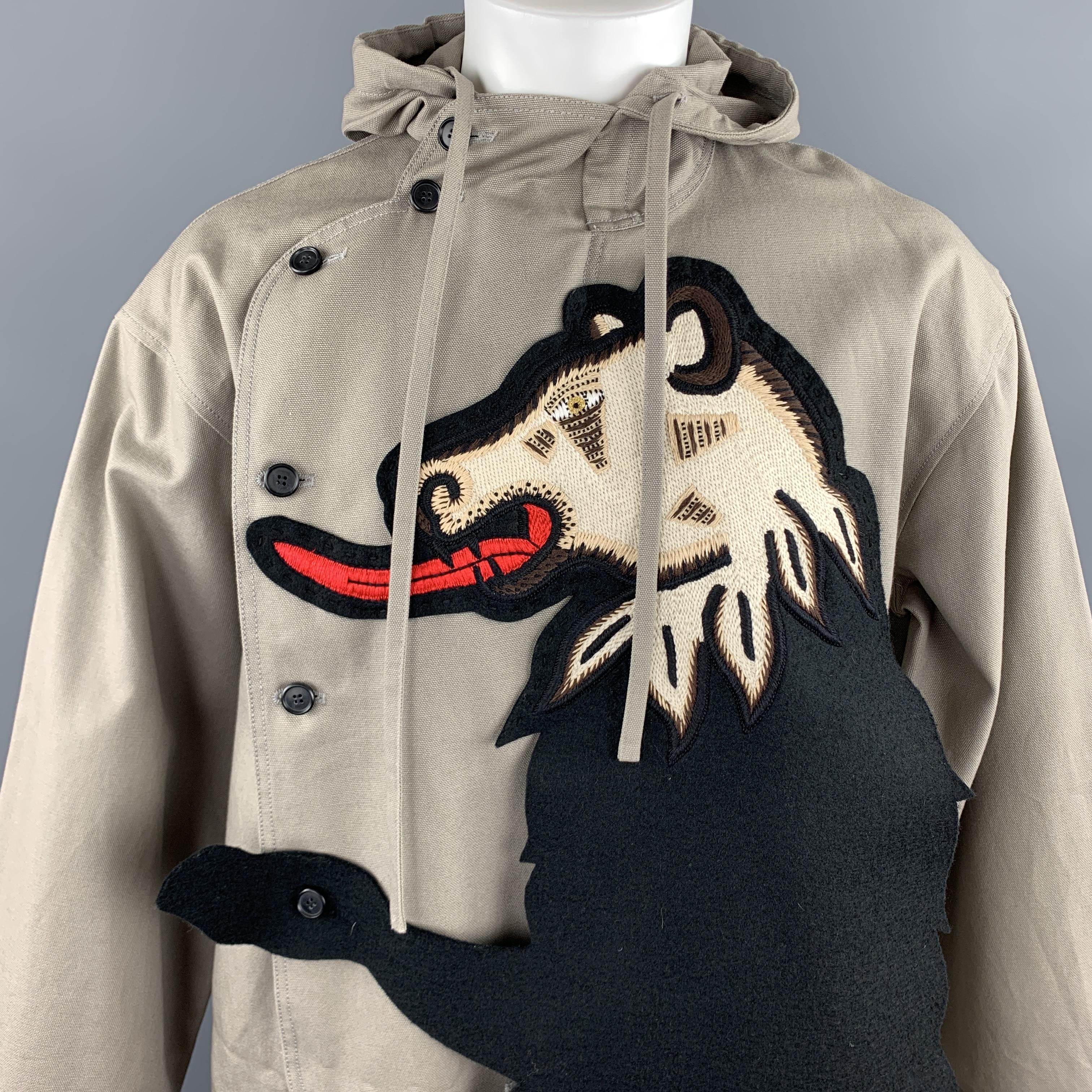 WALTER VAN BEIRENDONCK Fall / Winter 2017 runway jumpsuit comes in grey cotton canvas with a high hooded neckline, asymmetrical button closure, oversized fit, wide leg pants, and large embroidered bear overlay patch layer. Note: fits large. See