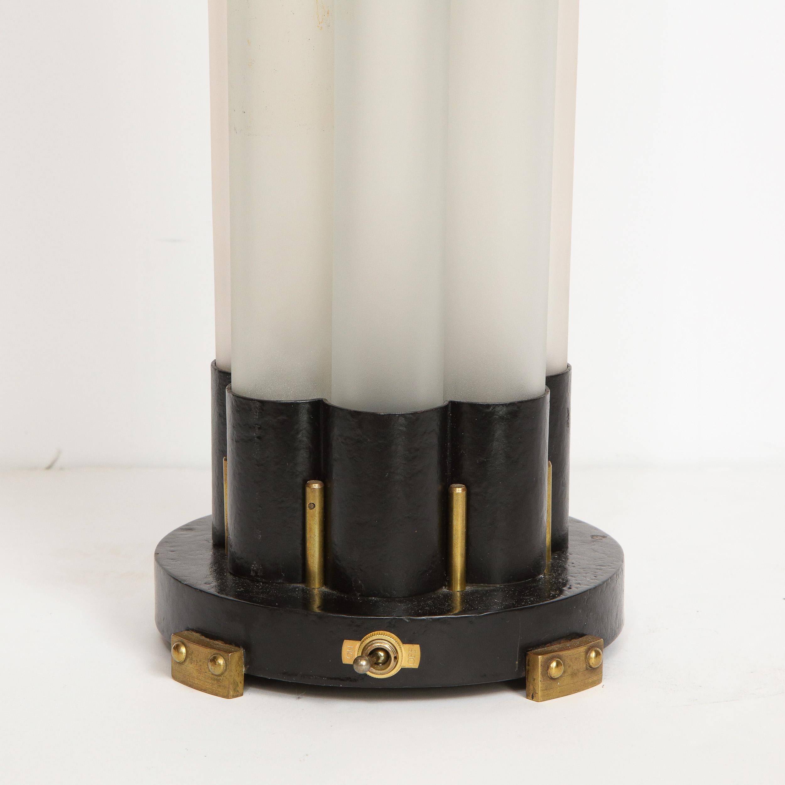 This elegant and graphic Art Deco Machine Age uplight was realized by the celebrated designer Walter Von Nessen circa 1935. It Features a circular black enamel base from which streamlined fittings in the same material ascend. These fittings hold a