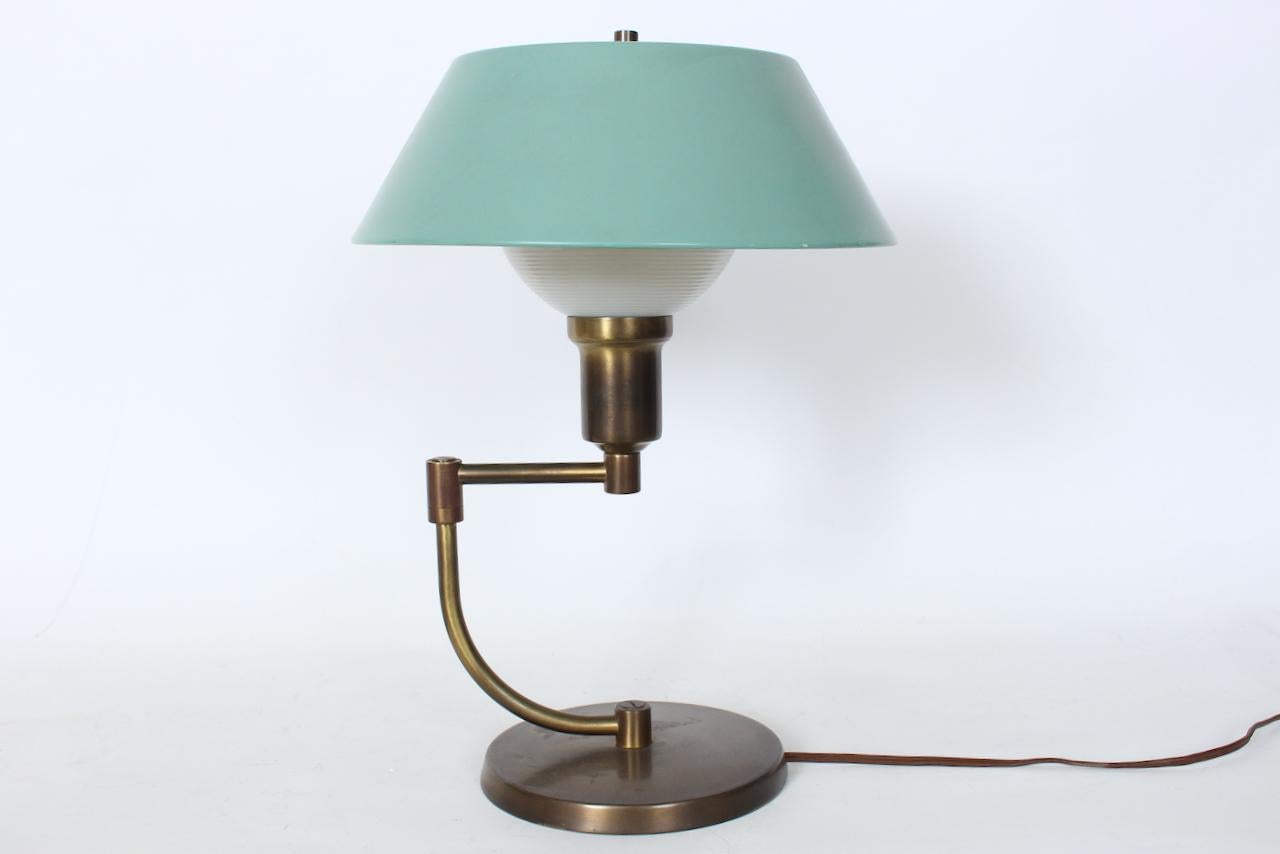 Walter Von Nessen Style Brass Swing Arm Desk Lamp with Pale Green Shade. Featuring a Brass column with extending and adjustable swing arm. extending to 16L. With original white smoothly ribbed Milk Glass liner shade (3.5H x 6D top) and original