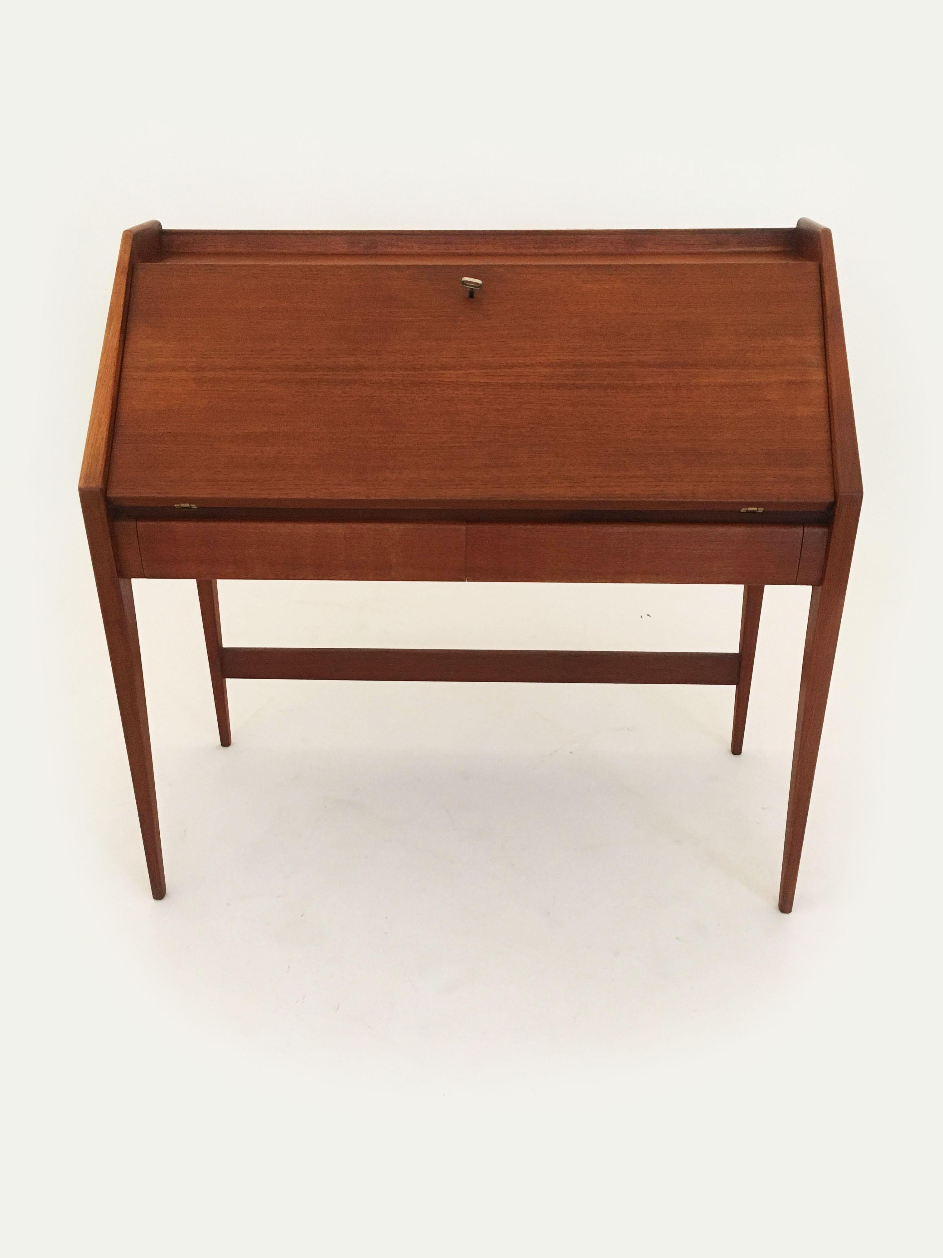 A rare vintage writing desk secretary in teak, designed by Walter Wirtz and manufactured by Wilhem Renz, Germany, 1960s. The quality and design is superb: an internal spring mechanism opens up with the turn of the key and two rail guards that