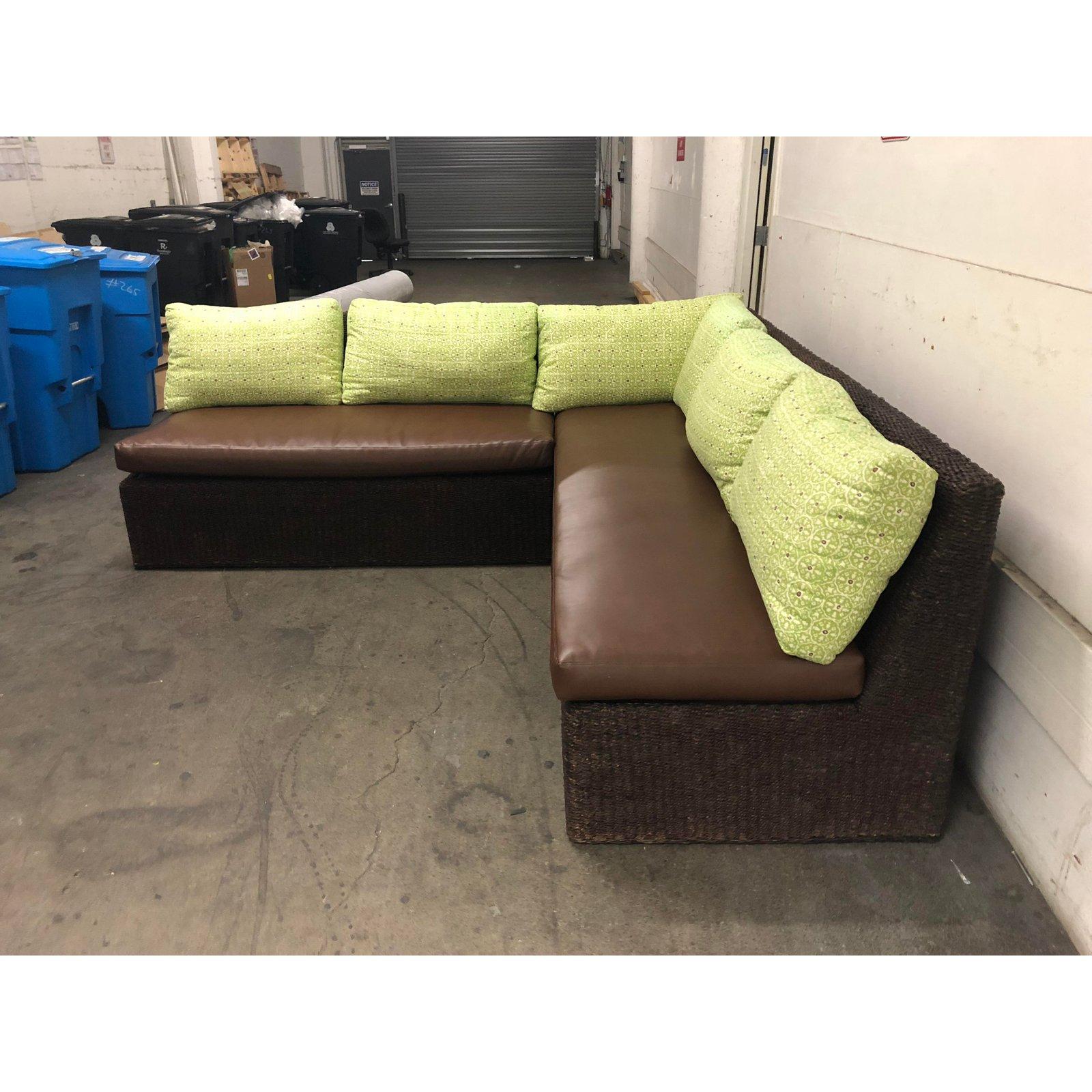 A two-part sectional from Walter's Wicker Works. A sloped back, open ends and firm leather seating comprise the basic structure of this sectional. Included are green wool canvas blend pillows with a sister parish style repeating royal seal design in
