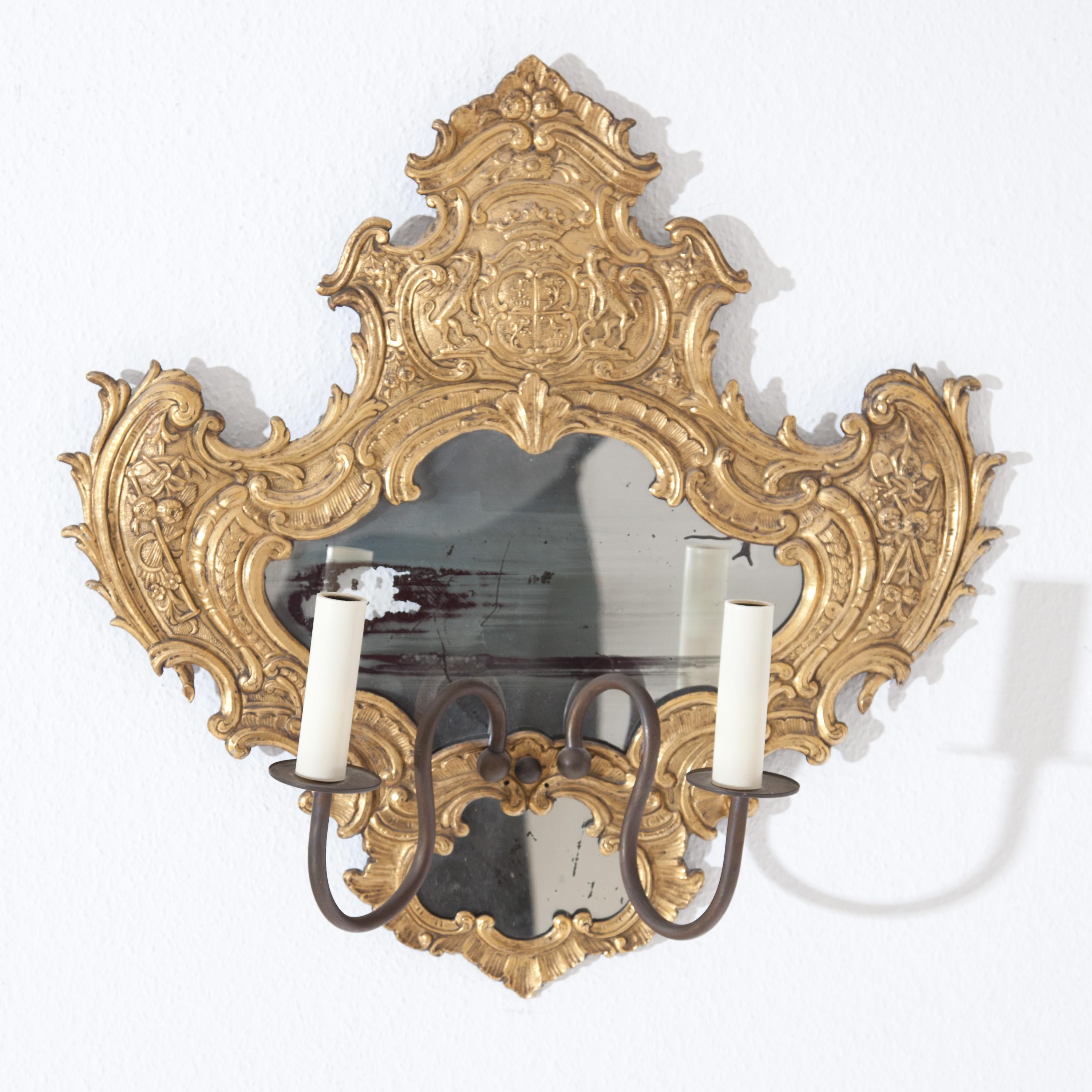 Application murale symétrique à miroir en bronze doré au feu. Le cadre au design émouvant est décoré de rocailles, de coquillages et de fermoirs, ainsi que d'outils de récolte et d'armoiries de couronnement. Deux prises de courant, électrifiées par