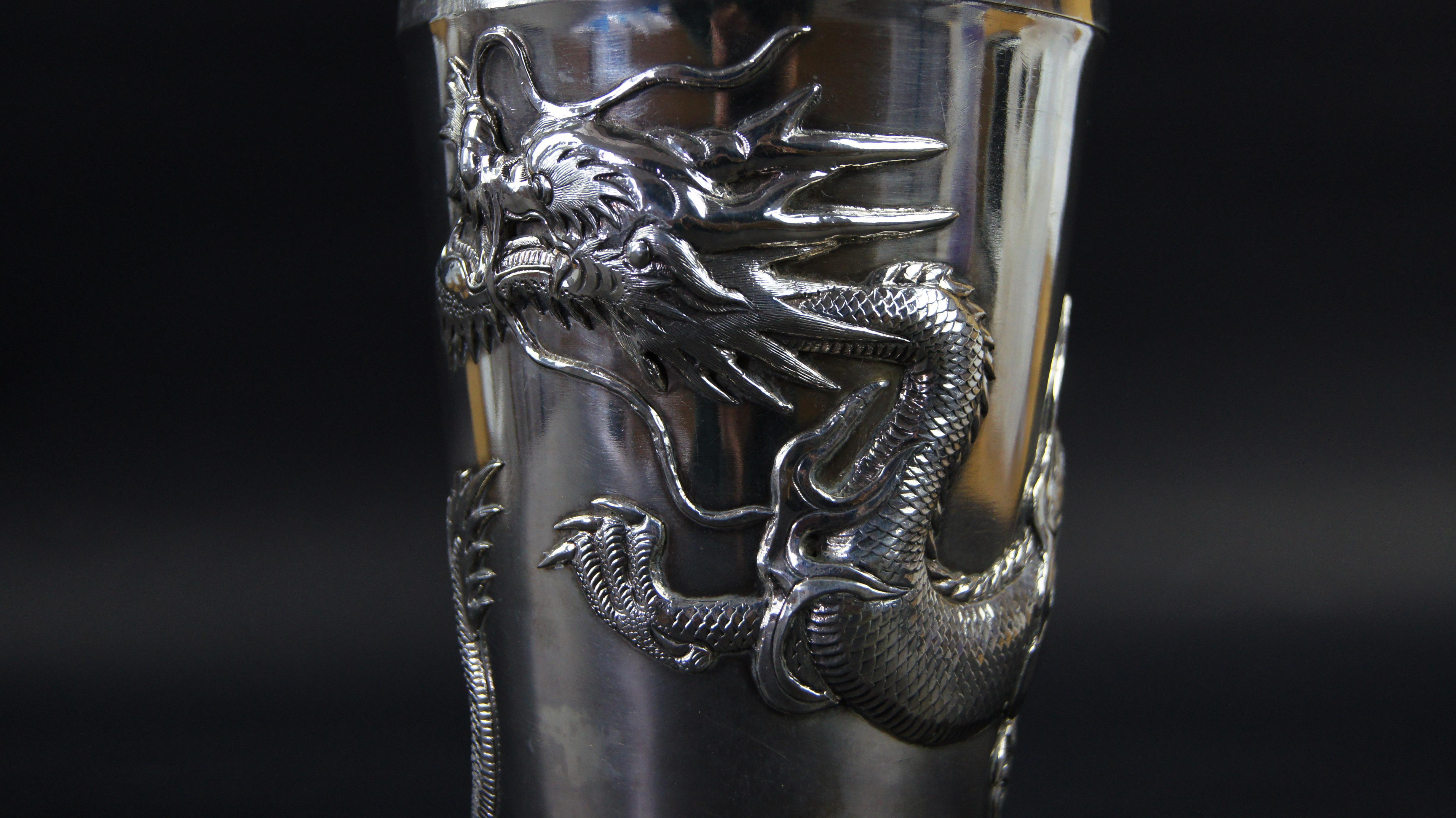 A Chinese Art Deco silver cocktail shaker by Wang Hing, circa 1920, of tapered form, the body embossed in high relief with a dragon, with stamps and hallmarks underneath.
 