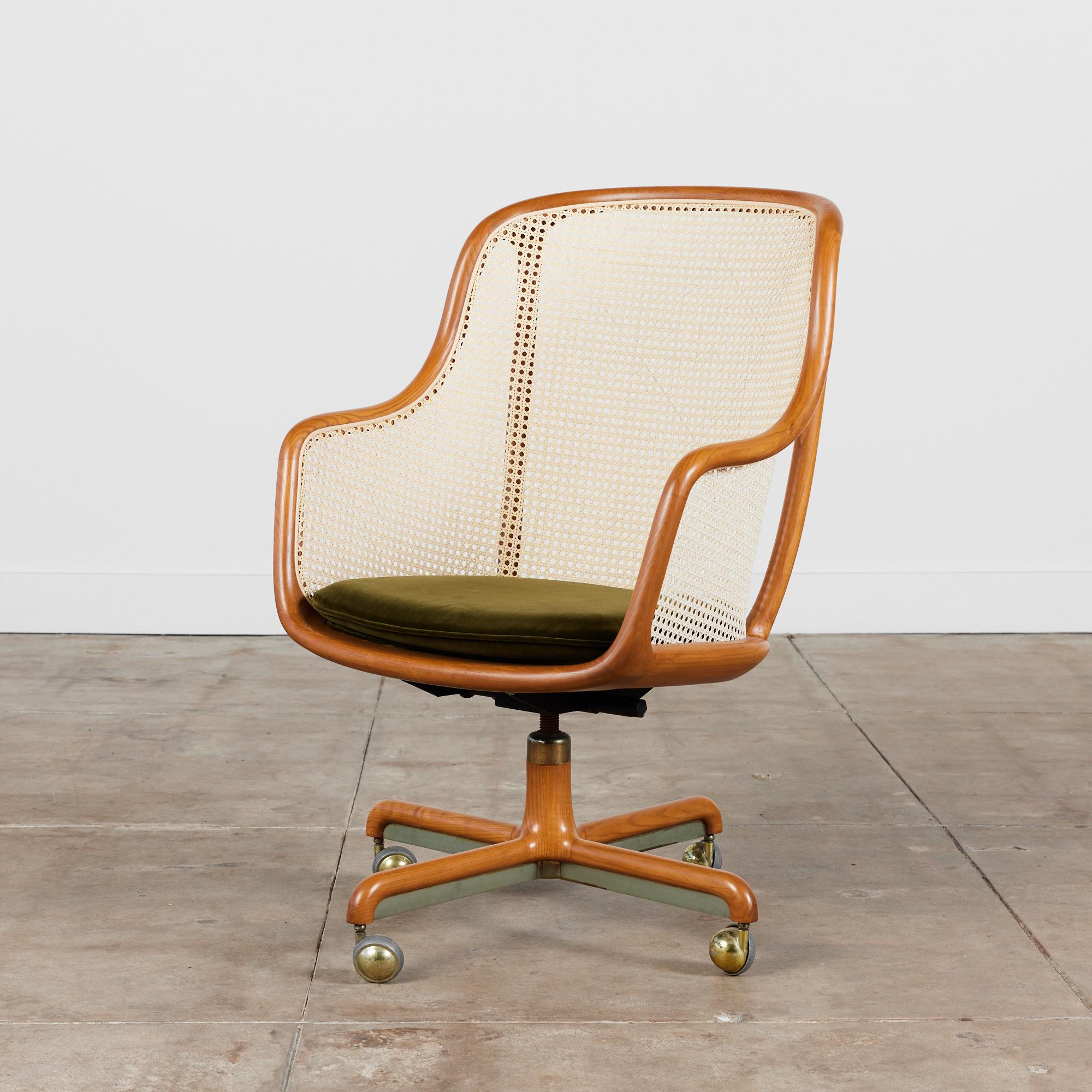 Ward Bennett Cane Desk Chair for Brickel Associates, circa 1960s, USA. This chair features an oak fame with cane back and armrests. The seat cushion has been newly upholstered in olive green velvet. The chair has both a tilt and swivel mechanism and