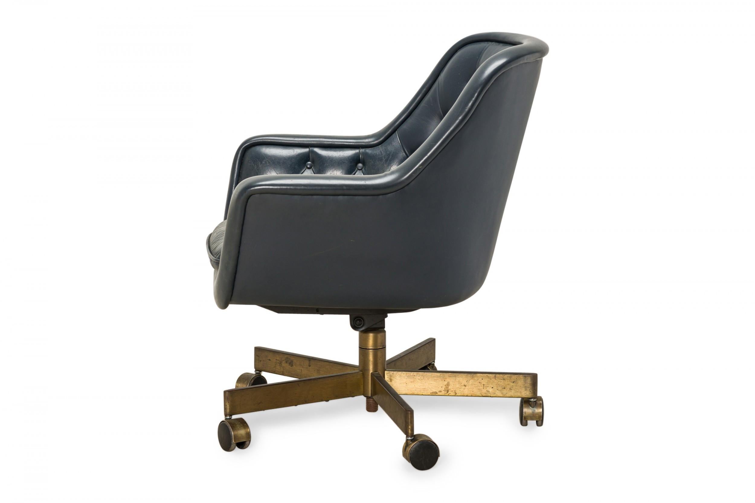 American Mid-Century swivel office chair with a button-tufted dark blue leather upholstered seat resting on a brushed brass pedestal base with five legs ending in brass and black plastic casters. (WARD BENNETT FOR BRICKEL ASSOCIATES, INC.)

Base
