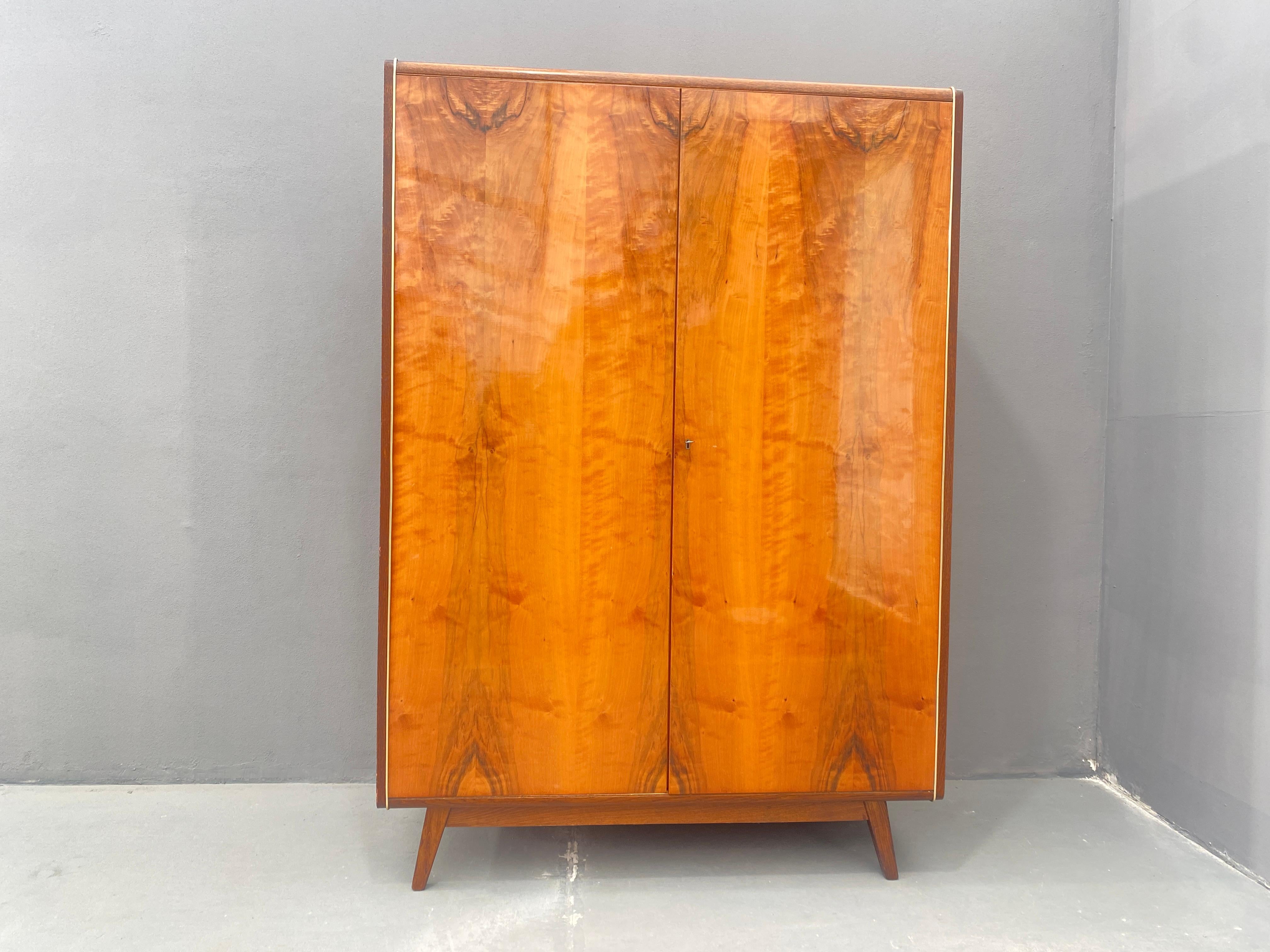 Cette armoire des années 1970 est un meuble solide avec une finition en placage de noyer. Il a été fabriqué par la société Jitona dans l'ancienne Tchécoslovaquie.  Il repose sur de subtils pieds, ce qui lui confère une apparence de légèreté. Les