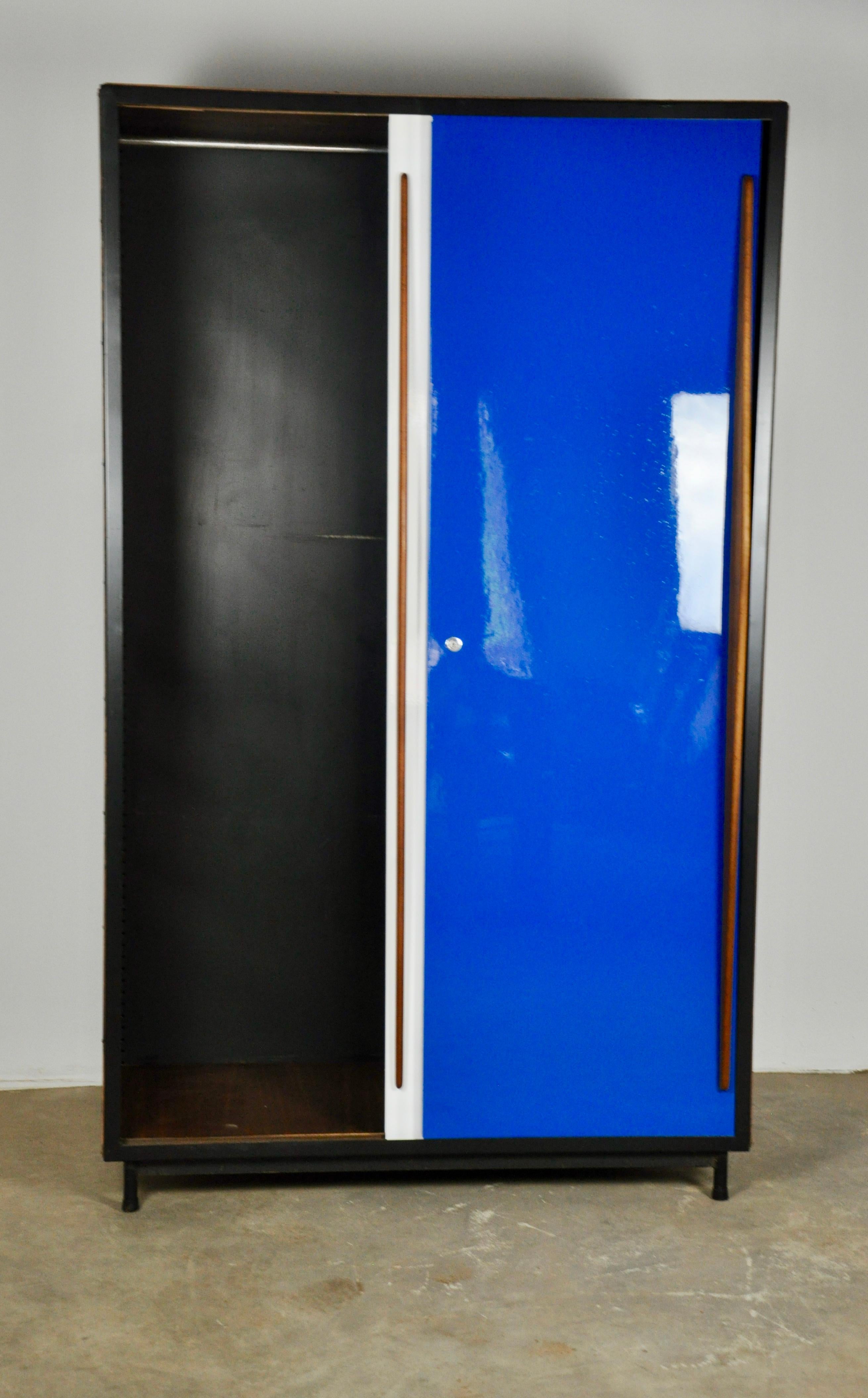 Wardrobe composed of two sliding doors in white and royal blue with a wooden handle. Interior bar to hangers.
