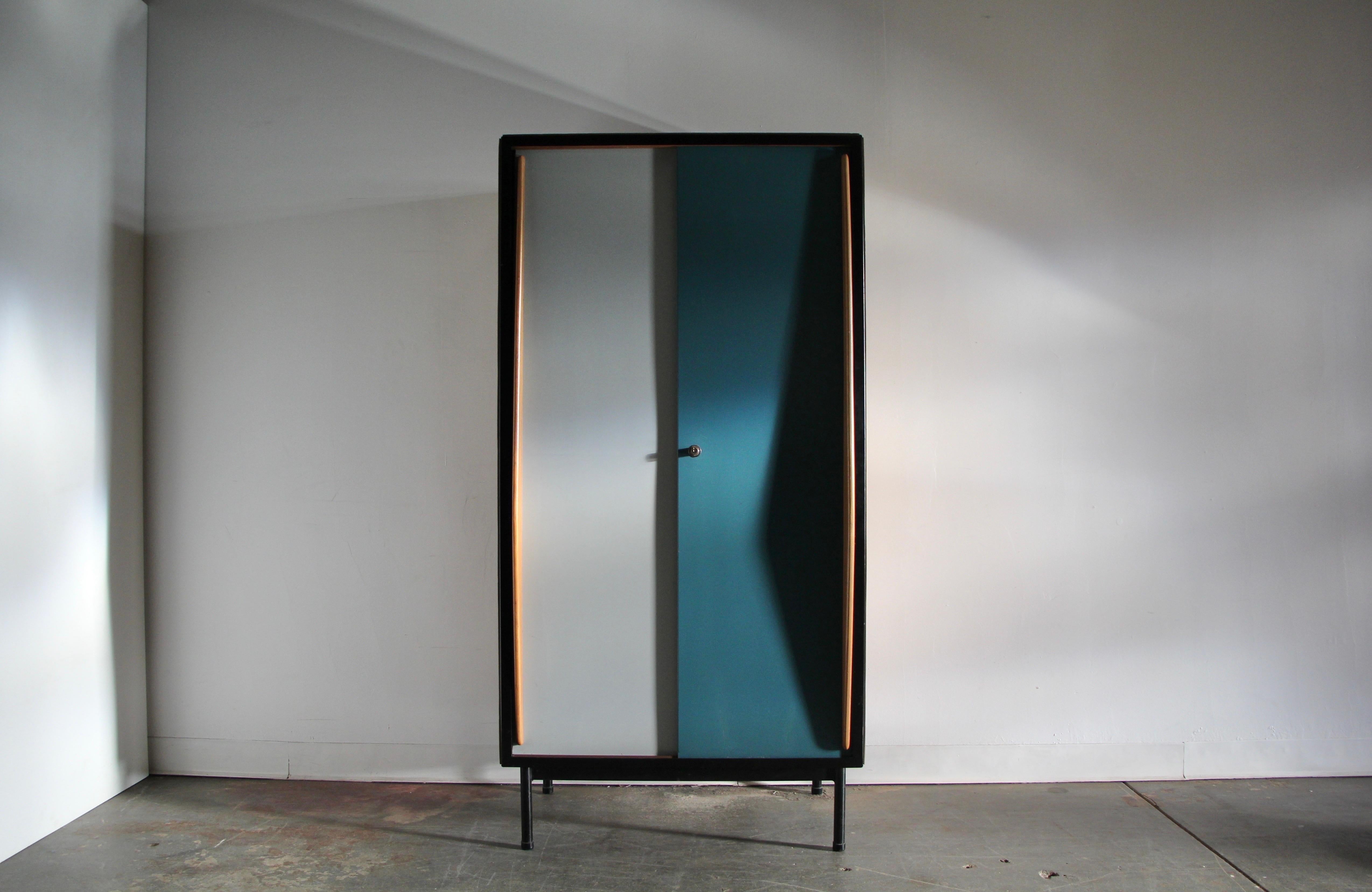 This striking cabinet was conceived by the Belgian designer Willy Van Der Meeren for Tubax, in 1952. This early example is constructed of lacquered plywood, mahogany, and metal. The front is adorned with two large sliding doors, one a muted blue