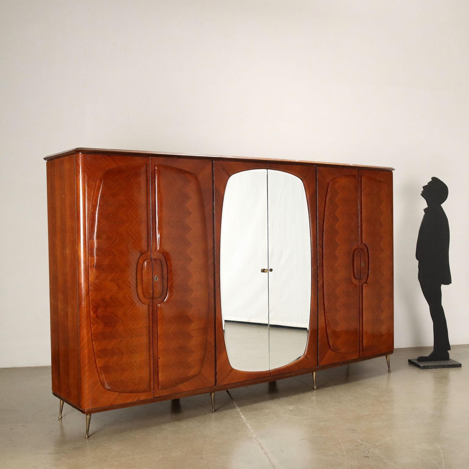 Wardrobe with 6 hinged doors, 2 of which with mirror; exotic wood veneered wood, brass legs.