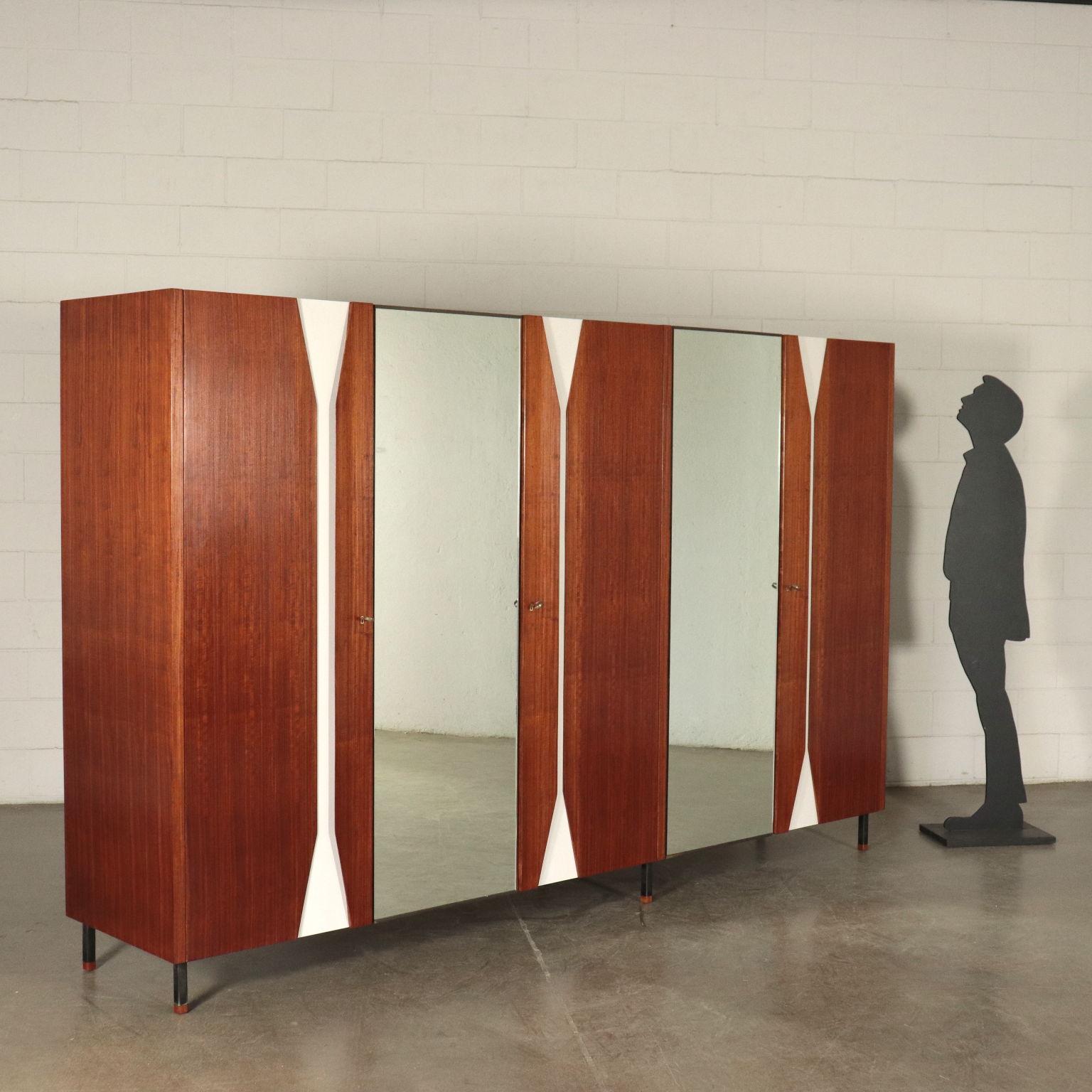 Wardrobe with 5 hinged doors, mahogany veneer, Formica inserts, mirrored glass, metal legs with wood cap.