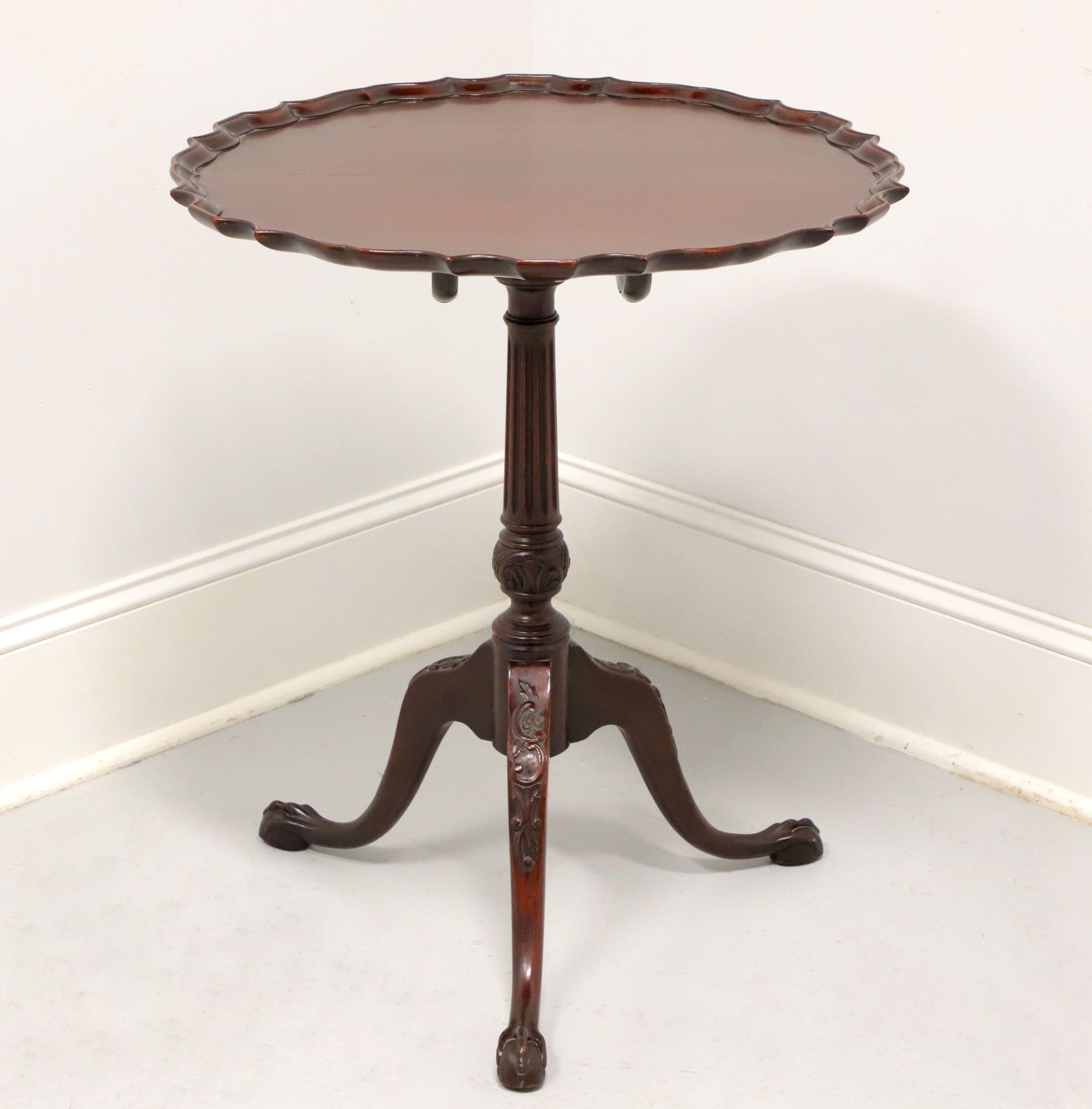An antique Chippendale style tilt-top pie crust table by Ware & Co, from their Collectors Group. Handmade of solid mahogany with scalloped edge top, tilt mechanism, brass latch, turned & fluted pedestal, three legs with carved knees and ball in claw