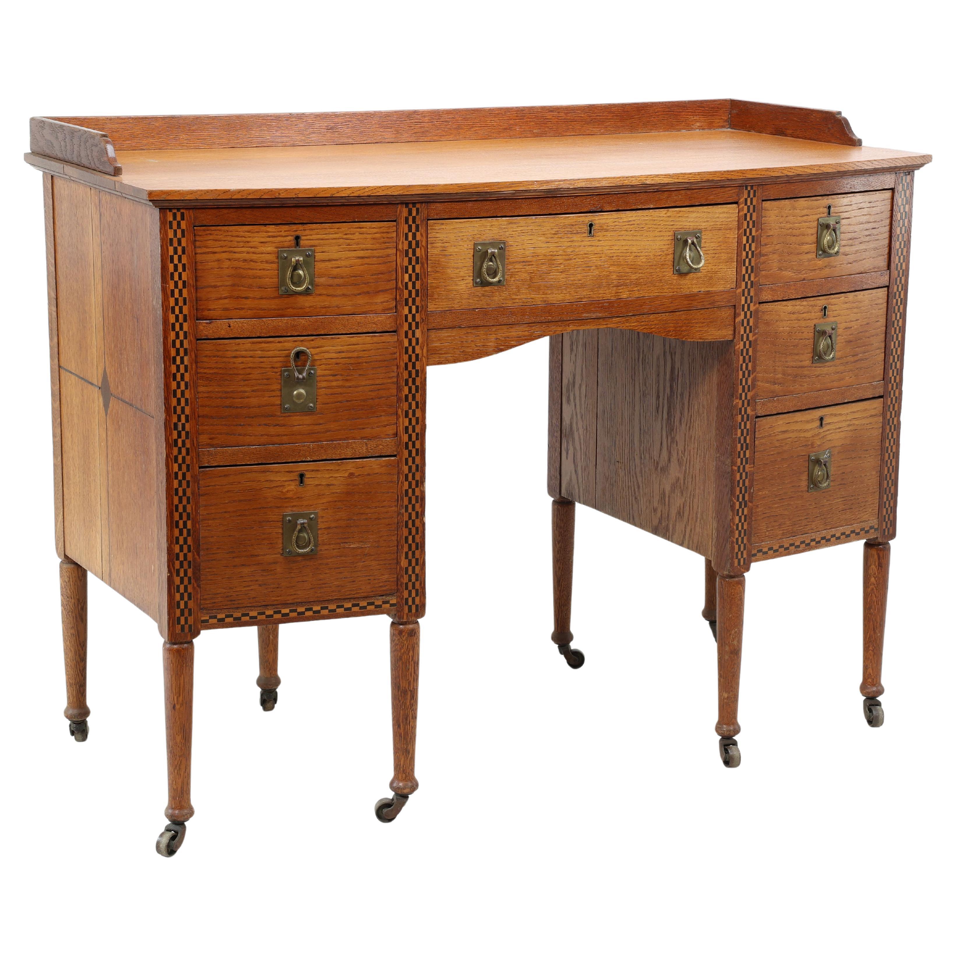 Waring & Gillow. Escritorio Arts and Crafts de doble cajonera, con frontal de arco y rodillera
