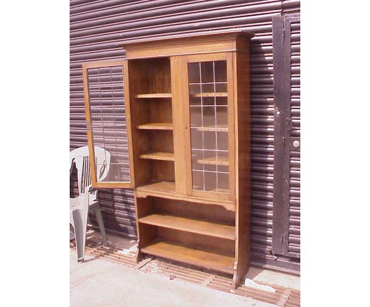 Waring & Gillows attributed a good quality Arts & Crafts oak bookcase with flaring cornice, ebony and fruitwood inlay to the top and the centre, with glazed and leaded doors opening to reveal adjustable shelves and two open shelves/display area