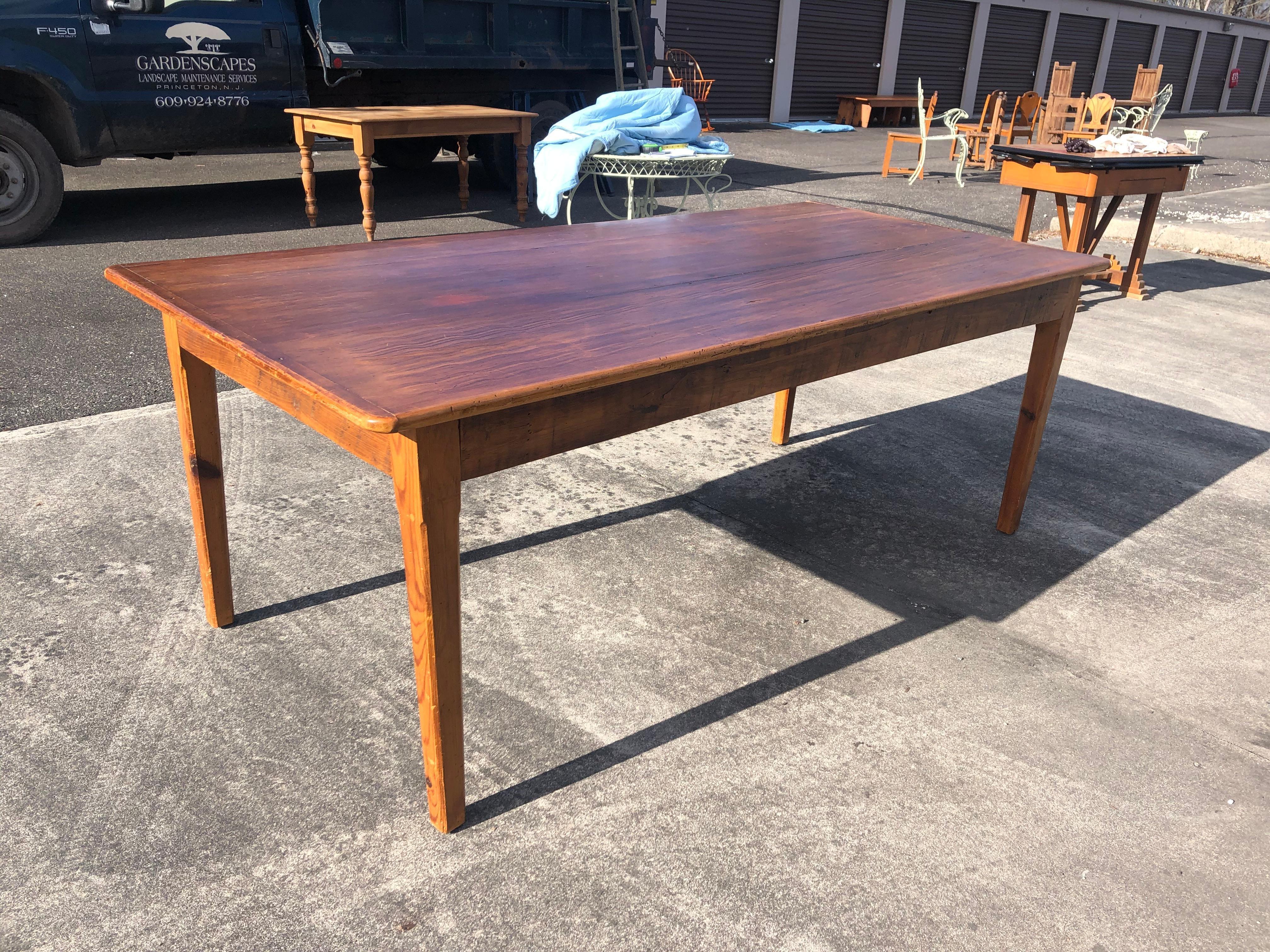 An almost 7 ft long rustic salvaged pine farm table having beautiful plank top with great character including natural worm holes and handsome grain. There are four simple tapered legs.
 Apron height from floor 24.75