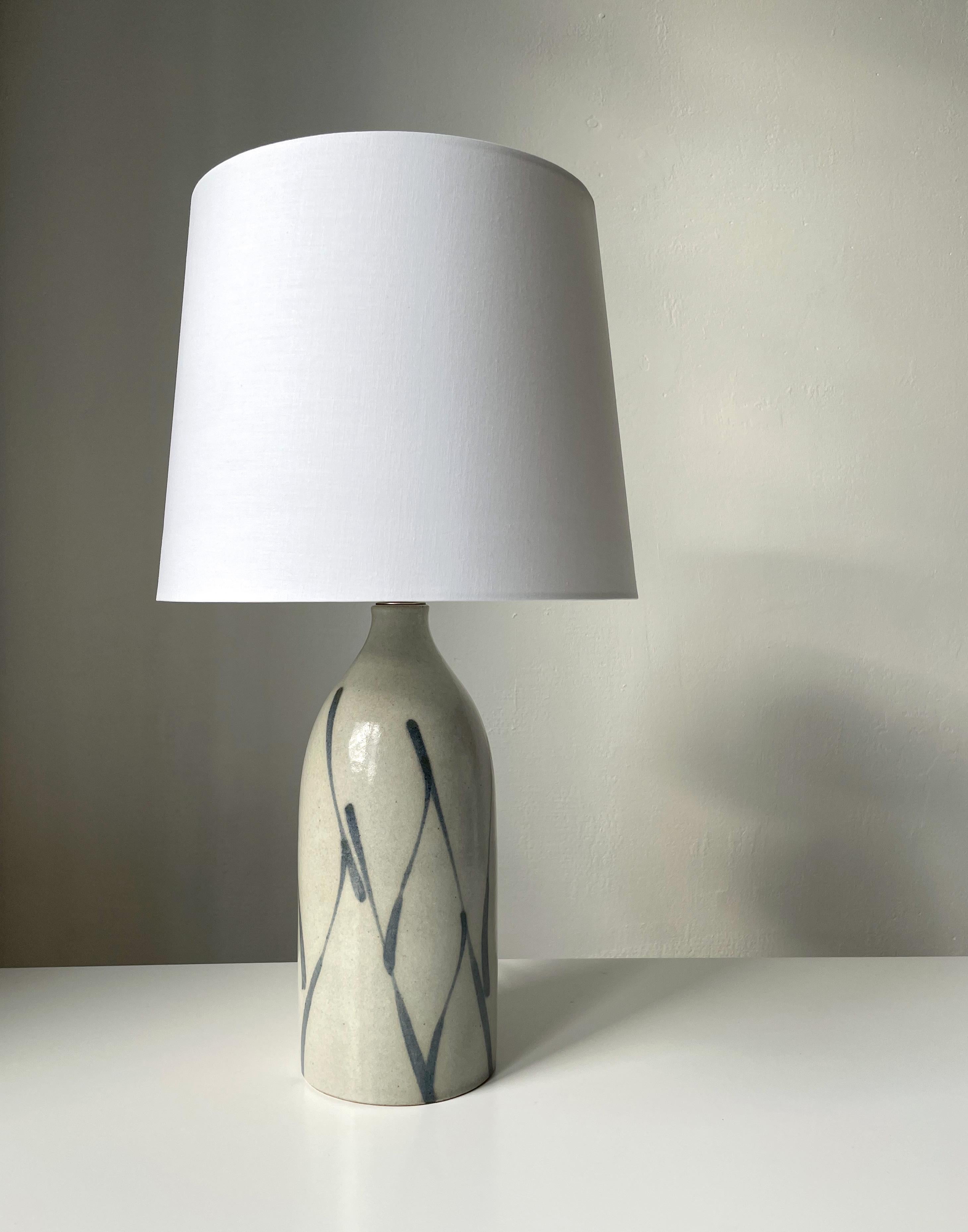 Warm grey glazed ceramic table lamp with darker grey soft, hand-painted, asymmetrical lines from top to bottom of the heavy, smooth bottle shaped body. Brass top. Manufactured by Kähler Keramik in the town of Naestved in the 1960s. Signed and