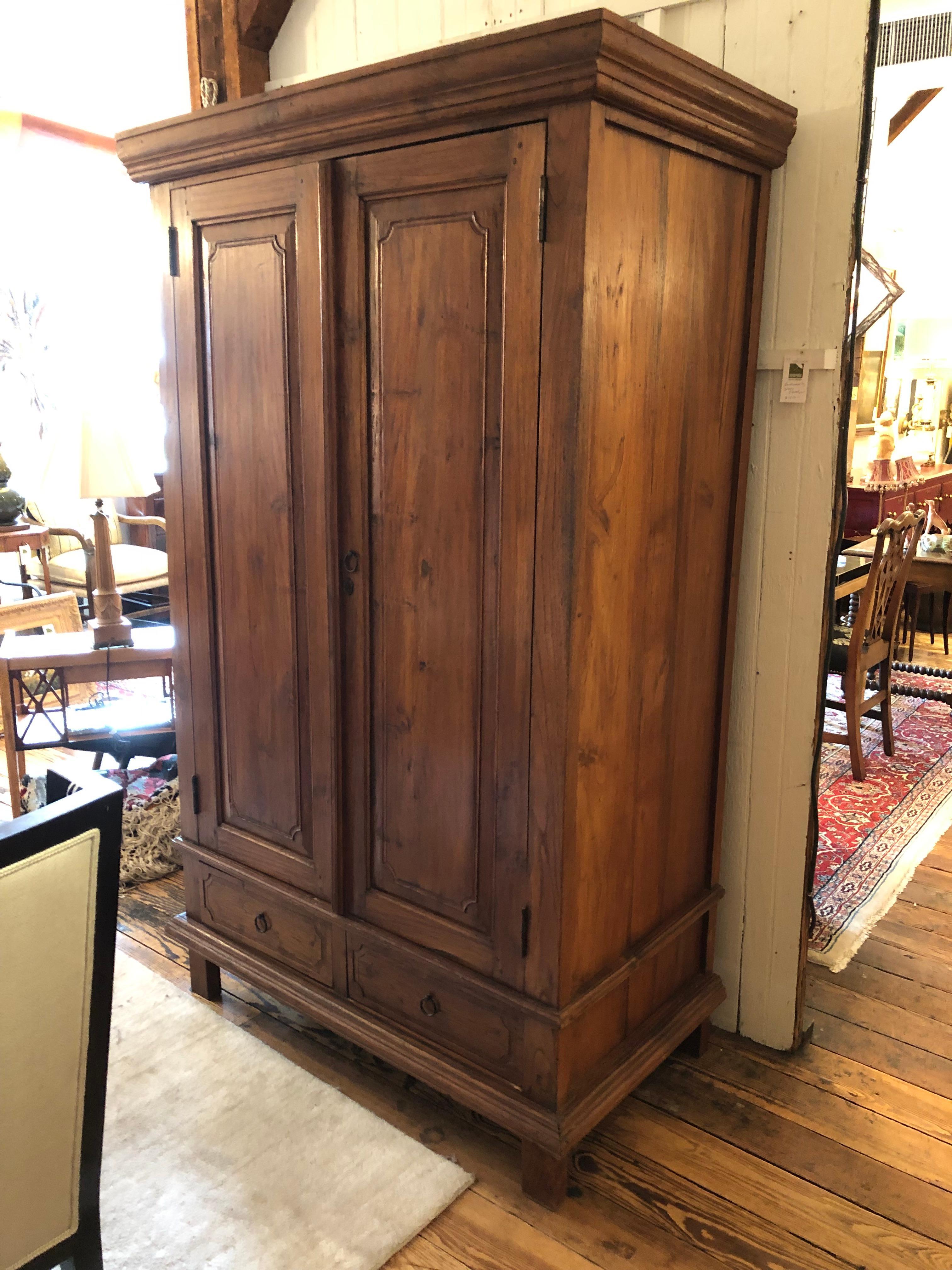 Character rich stained pine vintage armoire from Vermont, having beautiful paneled doors, original hardware, handsome top cornice and two drawers in the bottom. Interior has 4 shelves and a hole to allow stereo equipment wire. Lots of room for
