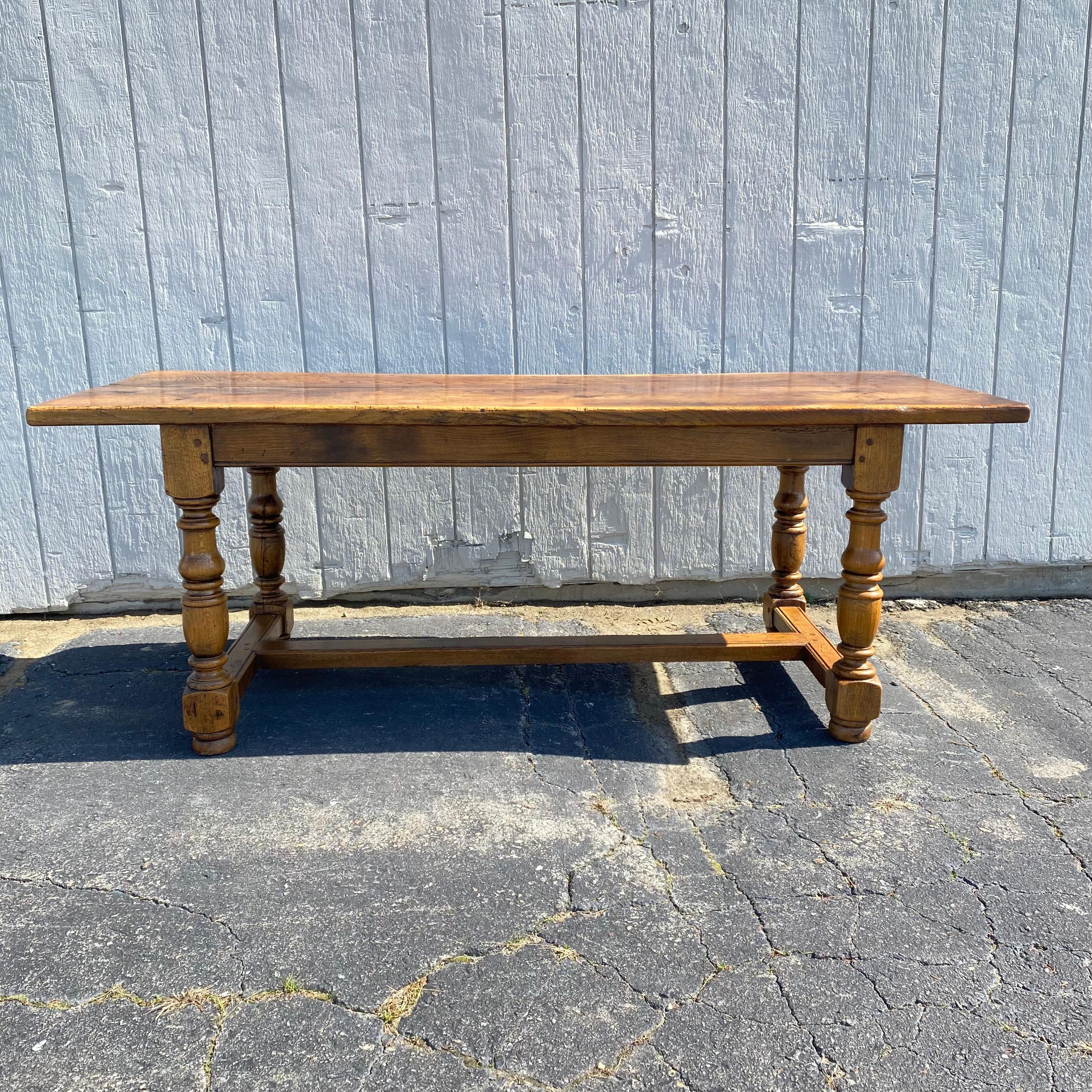 Classic country French Provincial farmhouse dining table or harvest table hand crafted from oak in the 19th century. The table features a thick plank top that is super solid. The trestle or refectory style table base has wood peg construction and