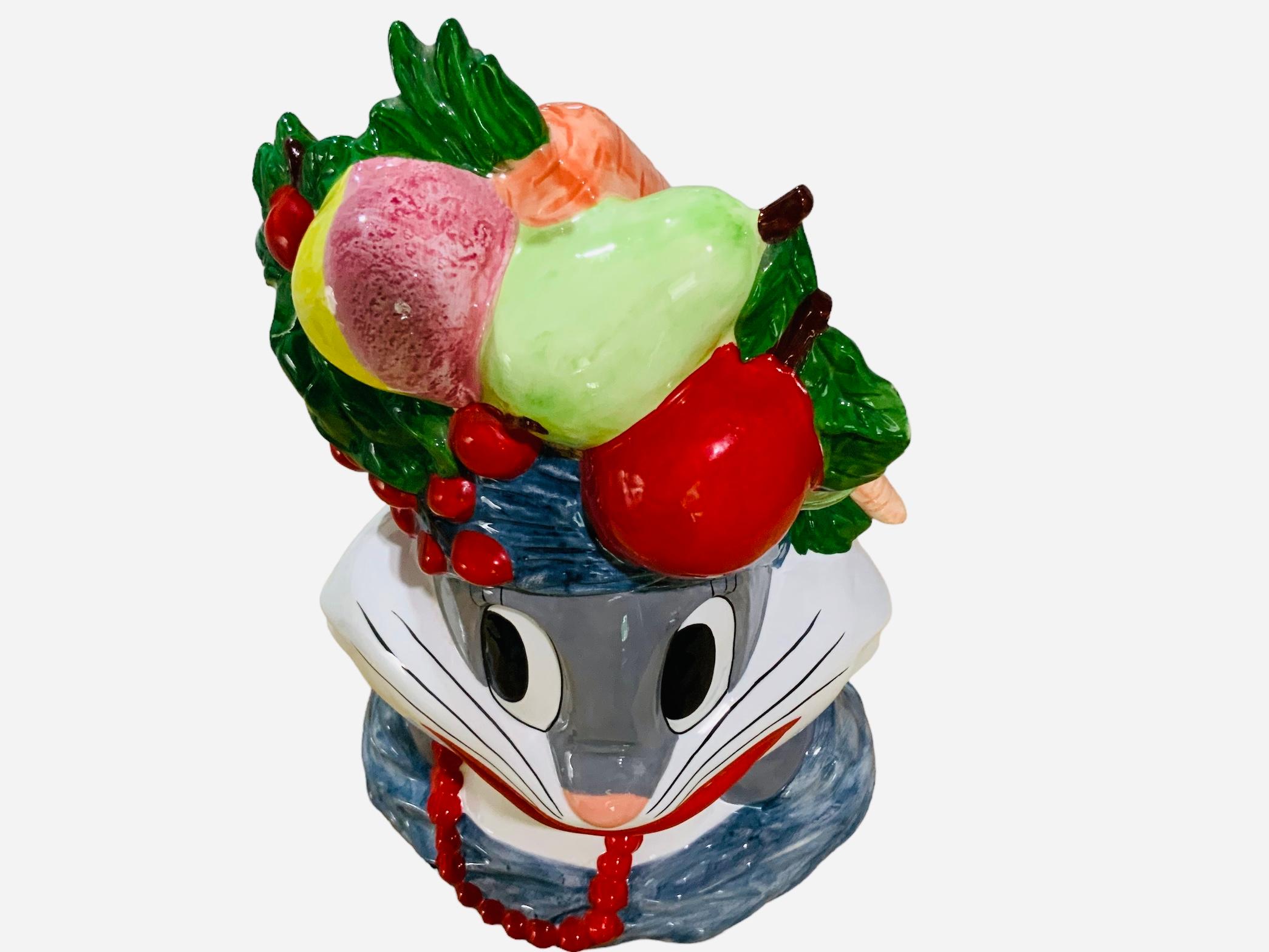This is a Warner Bros, Looney Tunes Bugs Bunny Carmen Miranda Cookie Jar. It depicts a hand painted ceramic cookie jar shaped as Bugs Bunny head adorned with a turban full of fruits. He is also wearing a red beads necklace. Below the base is