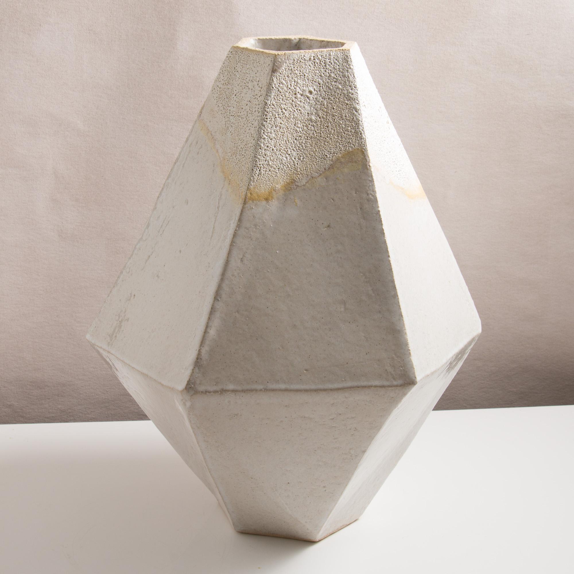 This large one of a kind ceramic vase combines complex geometric lines with the warmth and individuality inherent in handmade work. It was assembled from flat sheets of a sandy stoneware, into a geometric shape that feels both natural and entirely