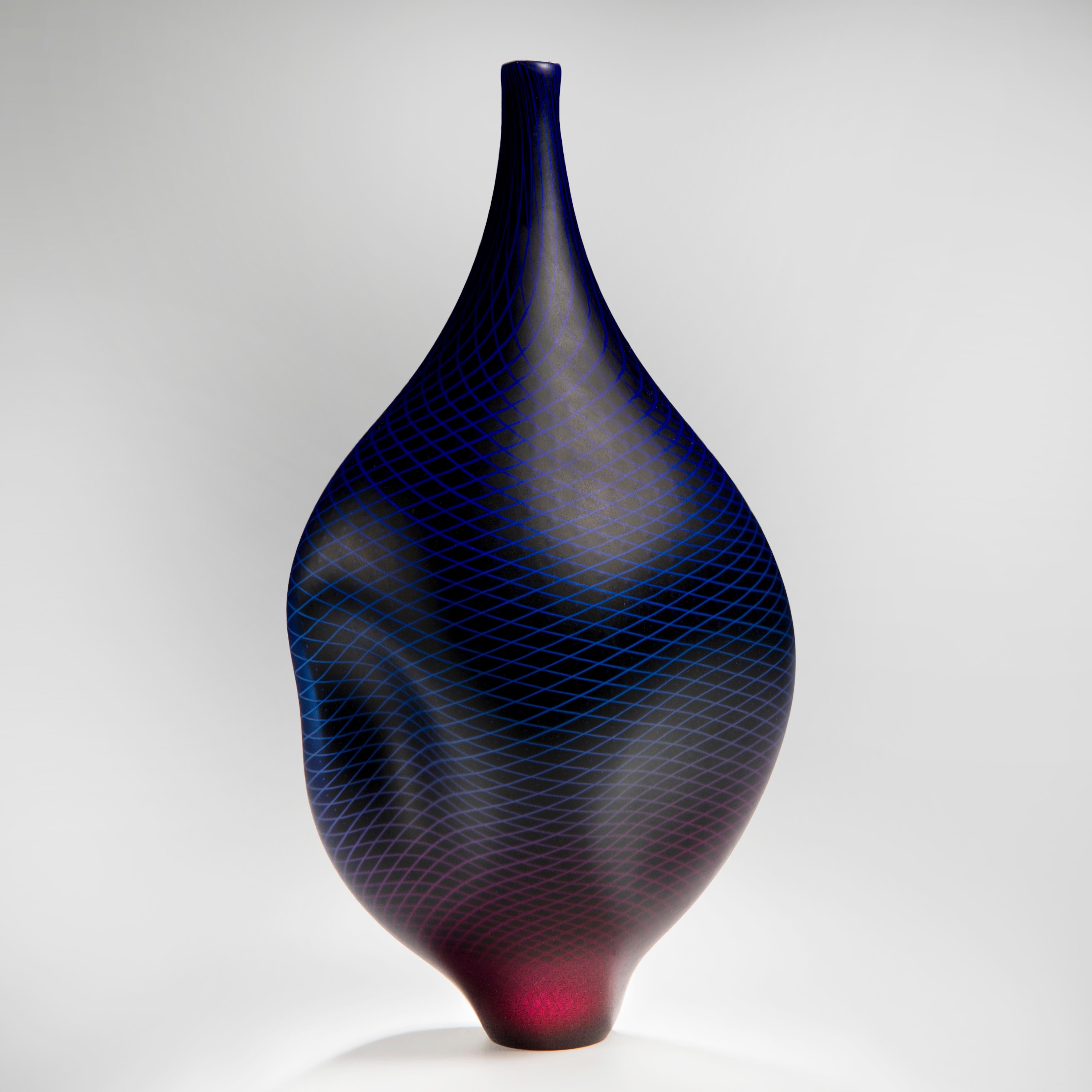 Warp & Fade 017 est un récipient unique en verre soufflé à la main avec de fins détails en canne blanche, créé par l'artiste britannique Liam Reeves. En incorporant des couches de verre, les couleurs supérieures bleu et rouge fusionnent pour créer