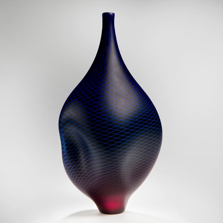 Warp & Fade 017 is a unique handblown glass vessel with fine white cane detail created by the British artist Liam Reeves. Incorporating layers of glass, the top colours in blue and red merge to create a larger spectrum, as the hues blur from one to