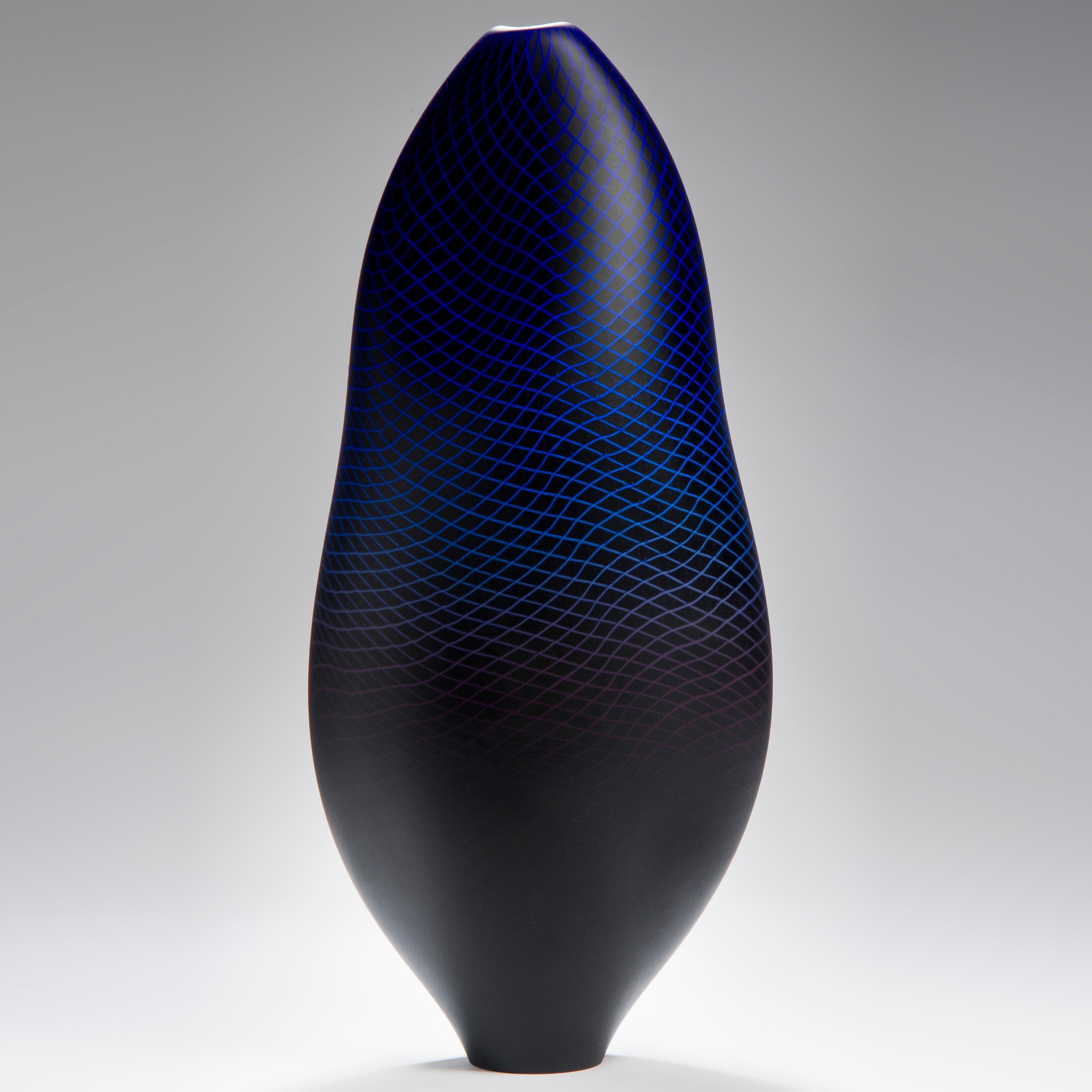 Warp/Fade/Distort 001, is a unique hand blown glass vessel with fine filigree white cane detail by the British artist Liam Reeves. The two colors of glass in purple and blue, merge in the making, over a layer of black glass, to create a larger