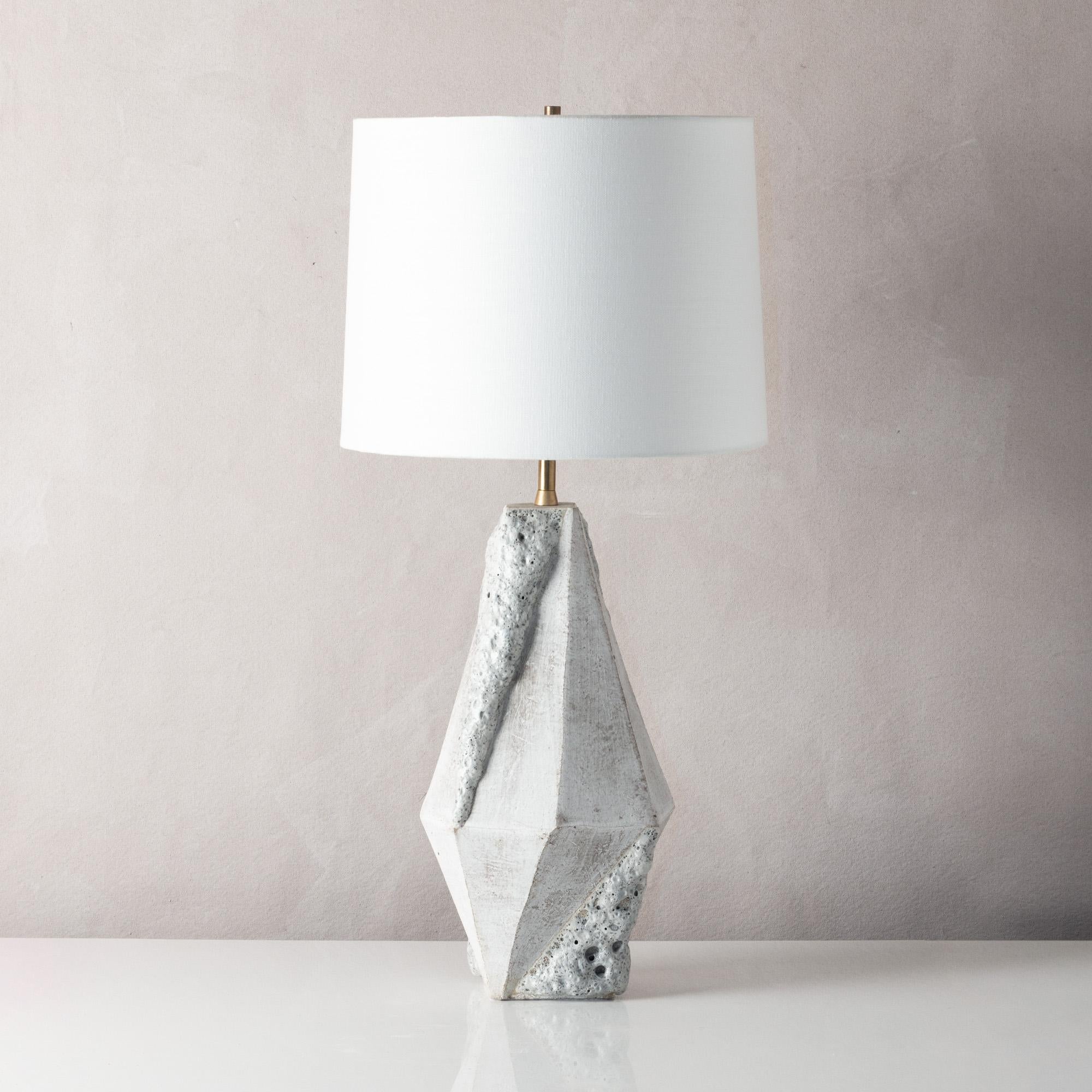 This dramatic ceramic table lamp features a complex geometric shape, accentuated by contrasting matte white and textured white glazes. Each piece is individually handmade and entirely unique. 

Available in two colors, with a white or black linen