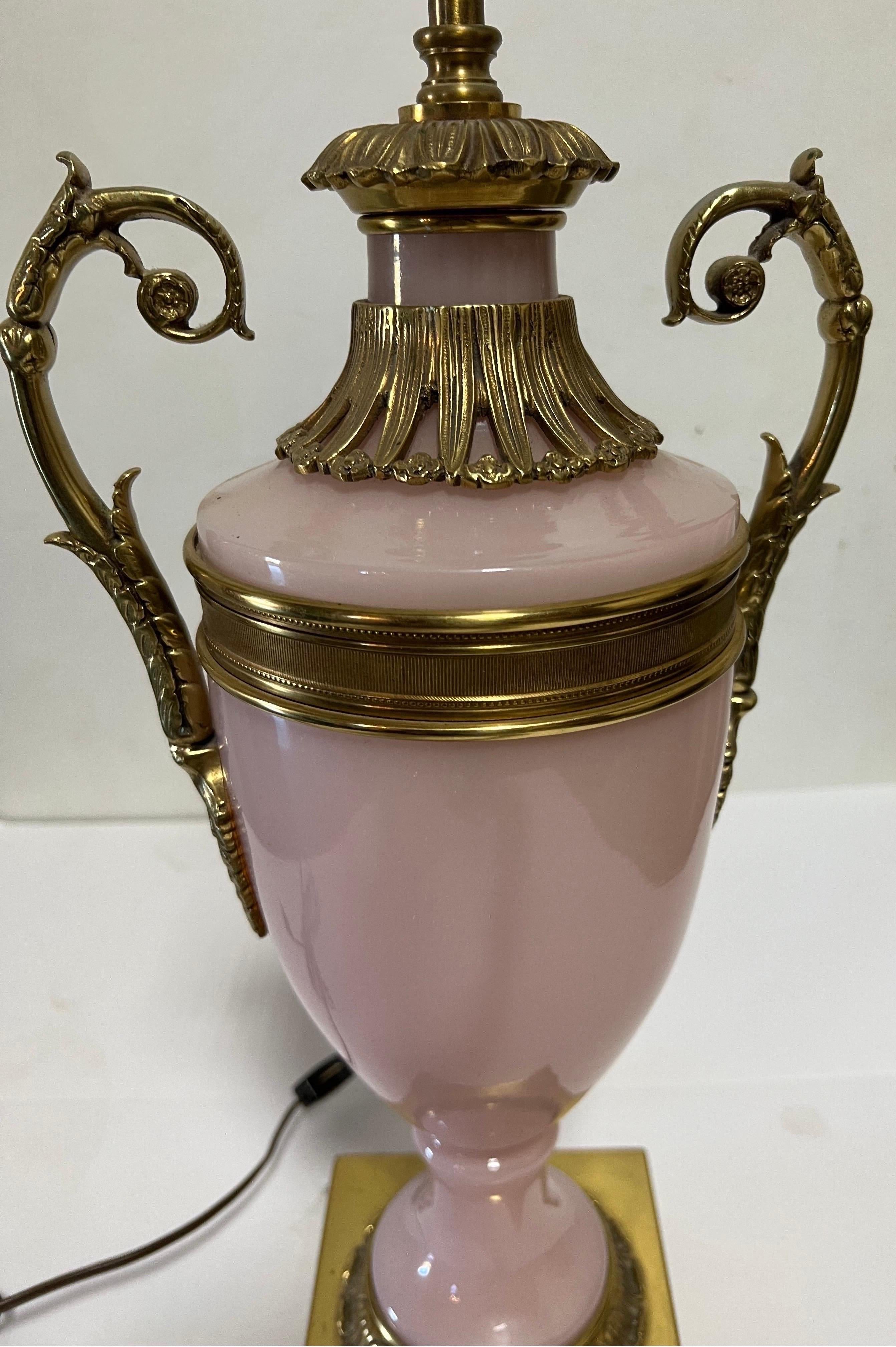 Warren Kessler pink glass and bronze table lamp. 

USA, circa 1950.

Signed with foil sticker.

Featuring an urn shape, complemented by bronze accents on a bronze plinth base. Brass hardware; wired for US; takes 2 standard US bulbs, 75 watts