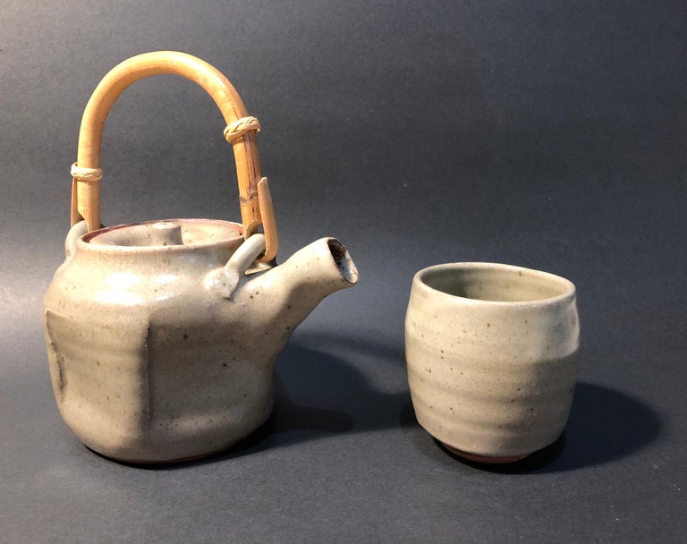 A complimentary pair of Warren MacKenzie pieces in grey glaze, which are being offered together:

Grey teapot with paddle marks
Stoneware
Measures: 7 1/2 x 7 x 6 inches (overall)
Impressed with the artists monogram at lower edge (see