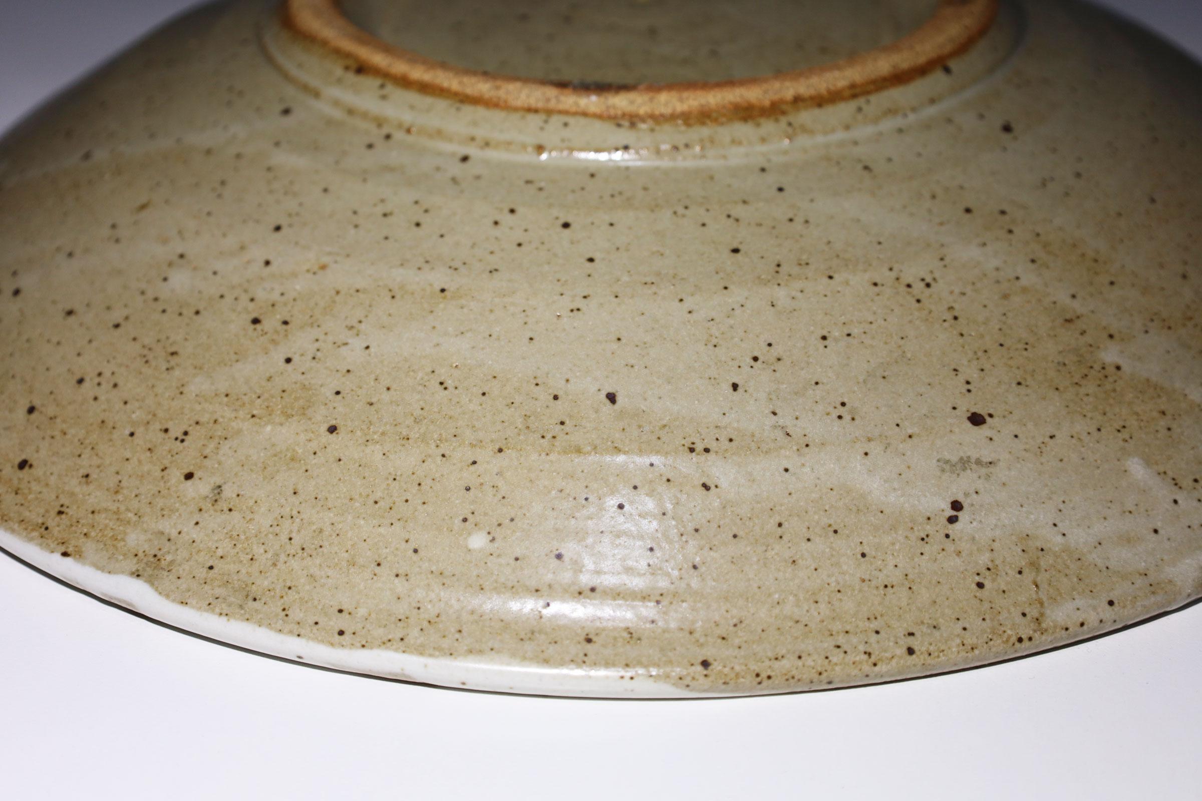 Grand plat en poterie de studio avec motif décoratif crème et marron. 

Warren MacKenzie est connu pour ses poteries fonctionnelles simples, tournées au tour, influencées par Bernard Leach et l'esthétique japonaise du travail de Shoji