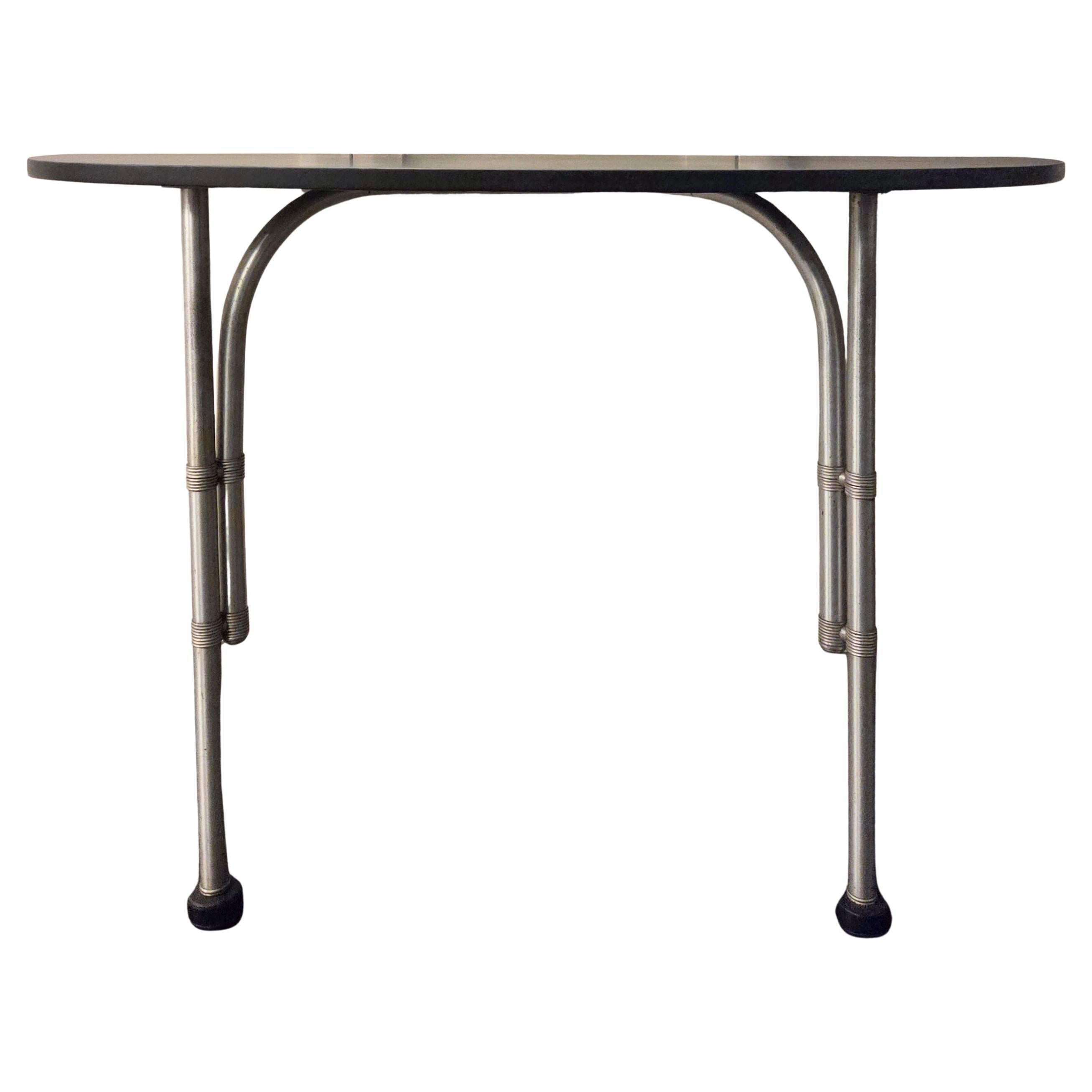A reserved and well-considered demi-lune console table by Warren McArthur, dating to around 1935. Works from this period reflect McArthur’s focus on lightweight structural systems and the expressive possibilities of anodized aluminum, and this