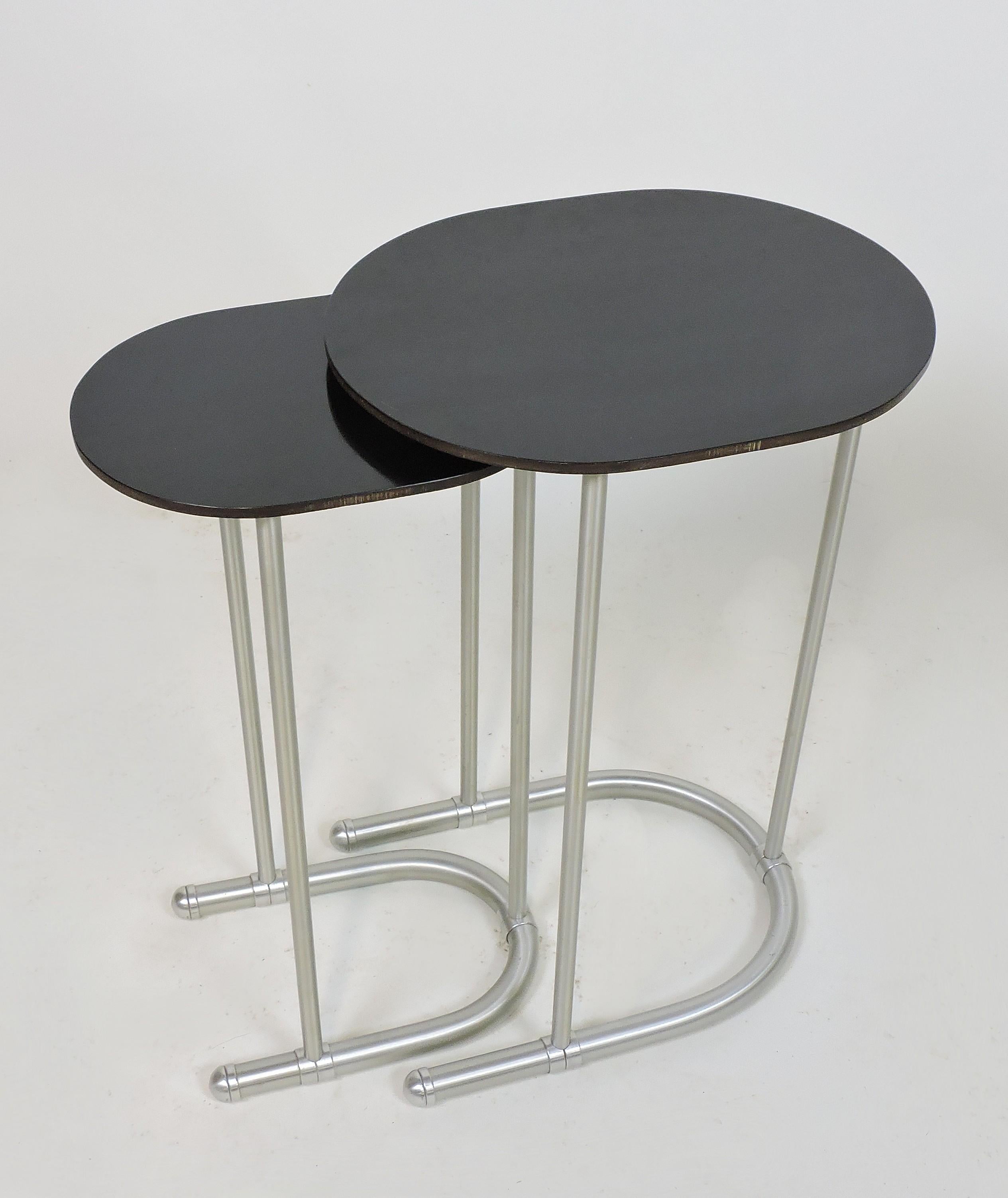Elegant set of two nesting tables with black laminate tops and aluminum bases designed by Warren McAthur and manufactured in the 1930s. The larger size is 20