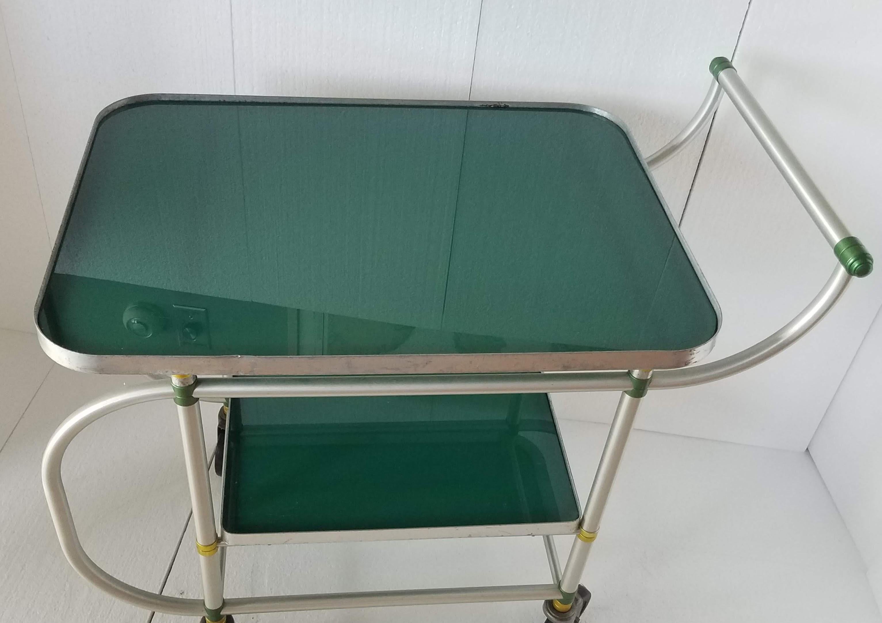 Rare Warren McArthur bar cart / service cart from the late 1930s with yellow and green turnings. 
Green Vitrolite shelf inserts are replacements.
Good condition.