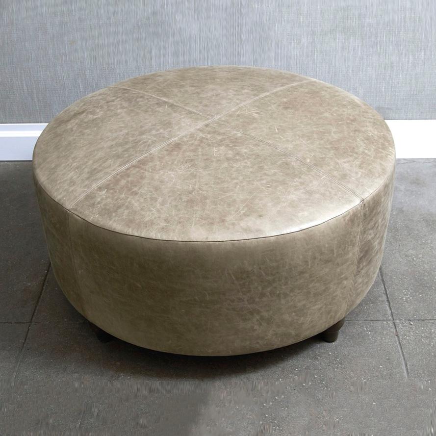 Circular, upholstered ottoman with top stitch detailing featuring traditional, turned wooden feet. The Warren ottoman frame is constructed using solid maple wood. Four finishes available for ottoman legs. Four standard fabric options available.