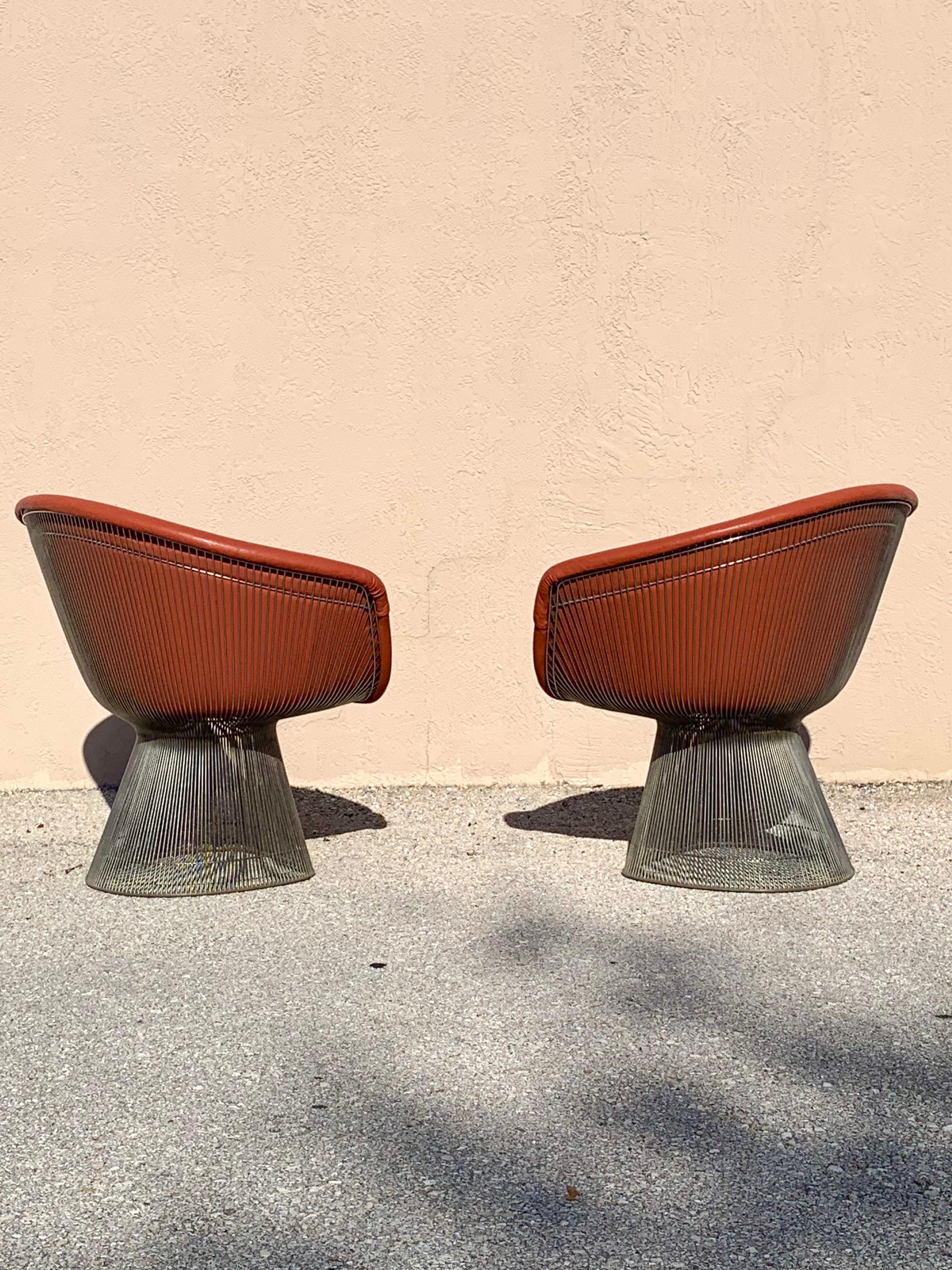 A pair of lounge chairs designed by Warren Platner for Knoll. Steel rod base finished in nickel. Upholstered in a burnt umber leather. Chairs were recovered from a South Florida estate where the owners had them upholstered in leather.