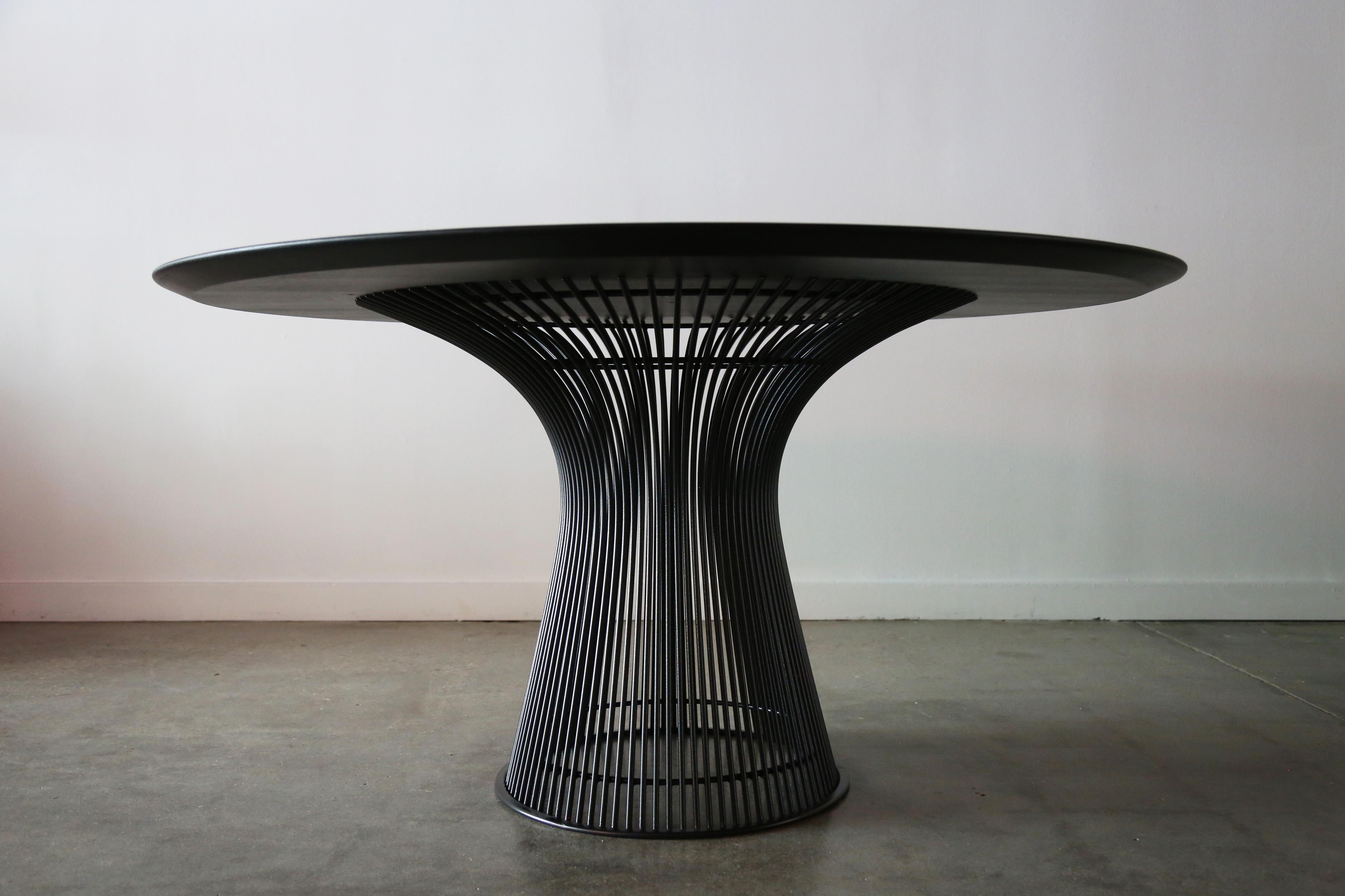 A 54” Ebonized oak veneer dining table designed by Warren Platner for Knoll. A sleek corseted wire frame base with a black bronze colored coating supports an ebonized oak top with a thin chamfered edge leaving a visually thin profile. Table