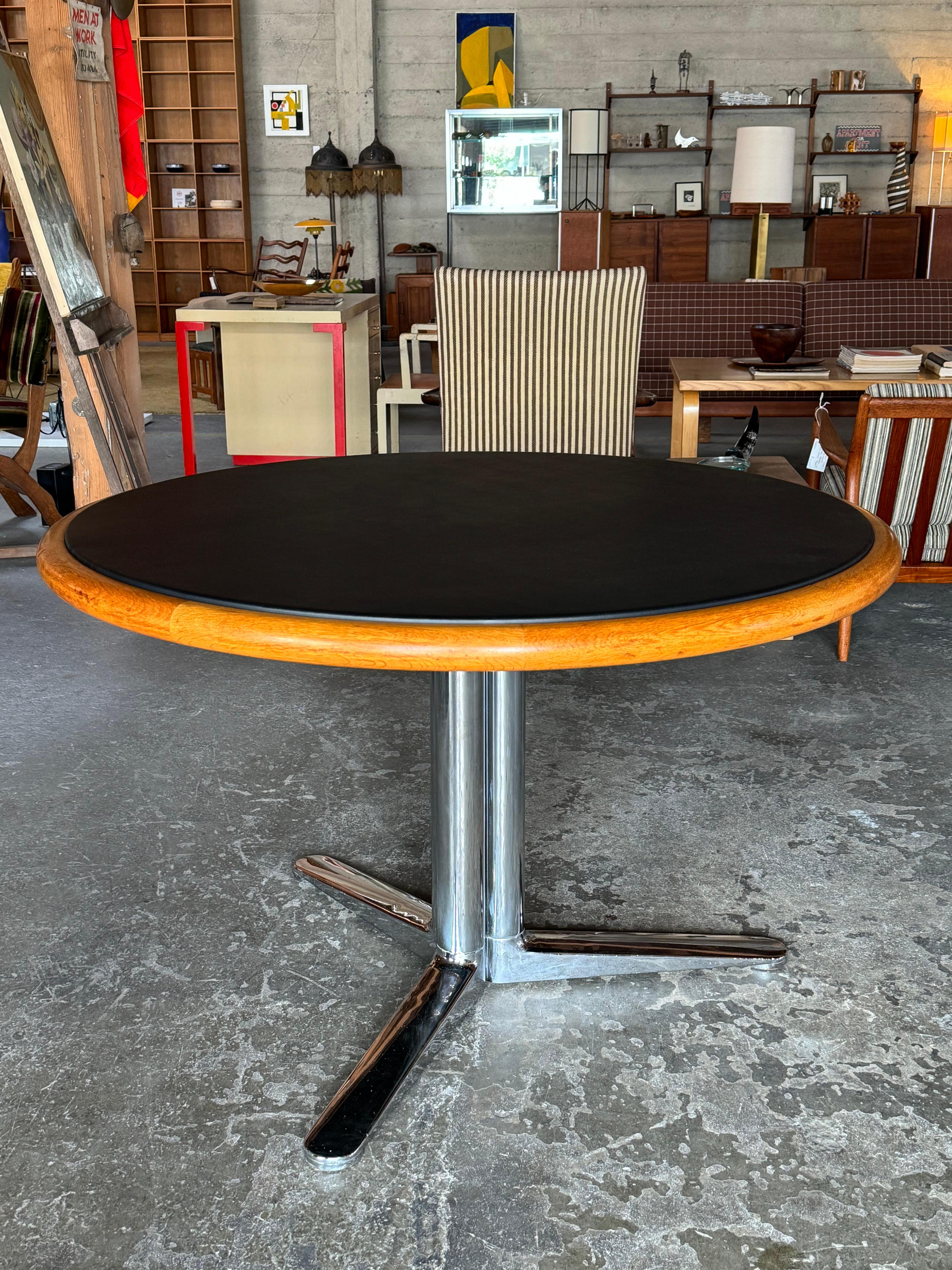 Extremely well crafted by architect Warren Platner for Knoll International, constructed of solid oak for the edge, a raised black leather top and a heavy chromed steel base. In near pristine vintage condition. As us about shipping options.