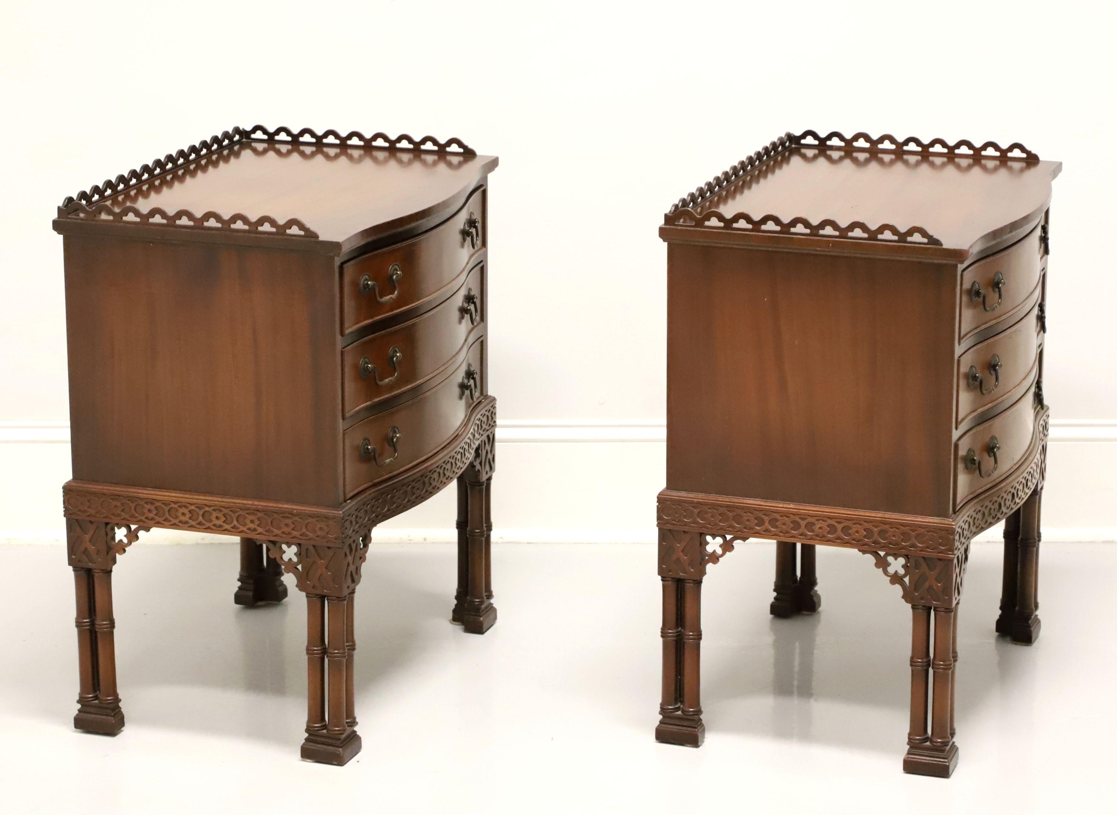 A pair of Chinese Chippendale style bedside chests by Warsaw Furniture Manufacturing Co. Mahogany with fretwork gallery, fretwork accents to apron & legs, bamboo like legs and block feet. Features the upper gallery and three drawers with brass