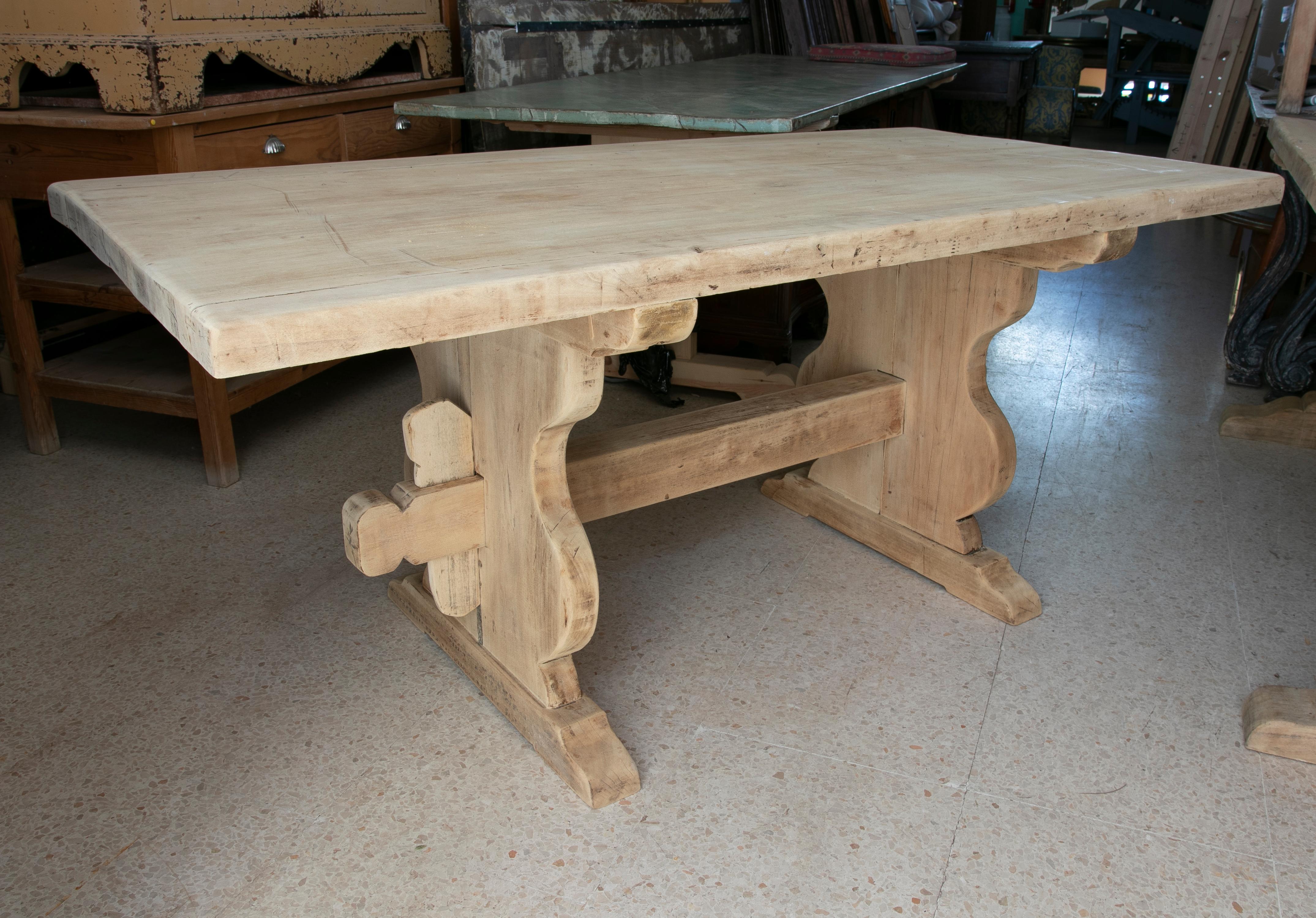 Washed wood table in its natural colour with crossbar at the bottom.