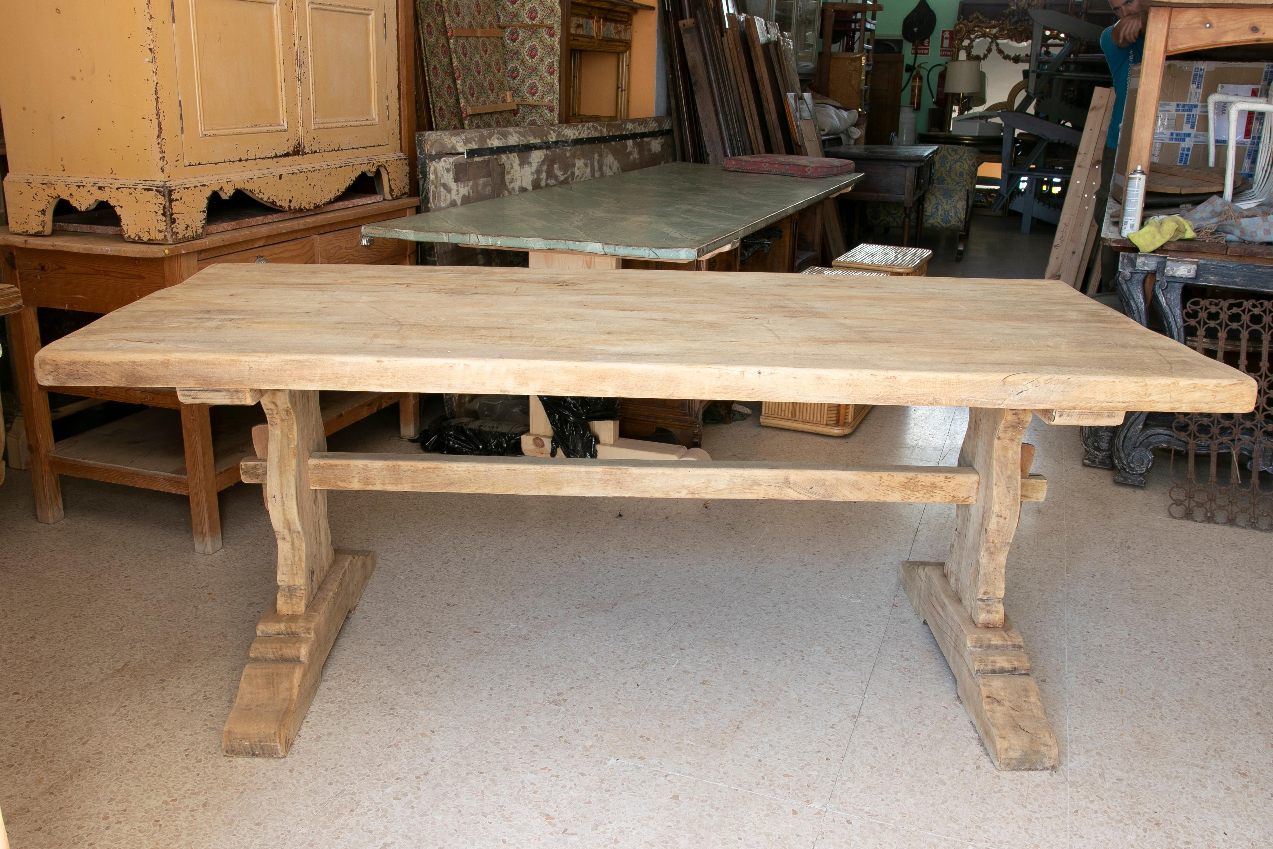 Tisch aus gewaschenem Holz in seiner natürlichen Farbe mit Querbalken an der Unterseite