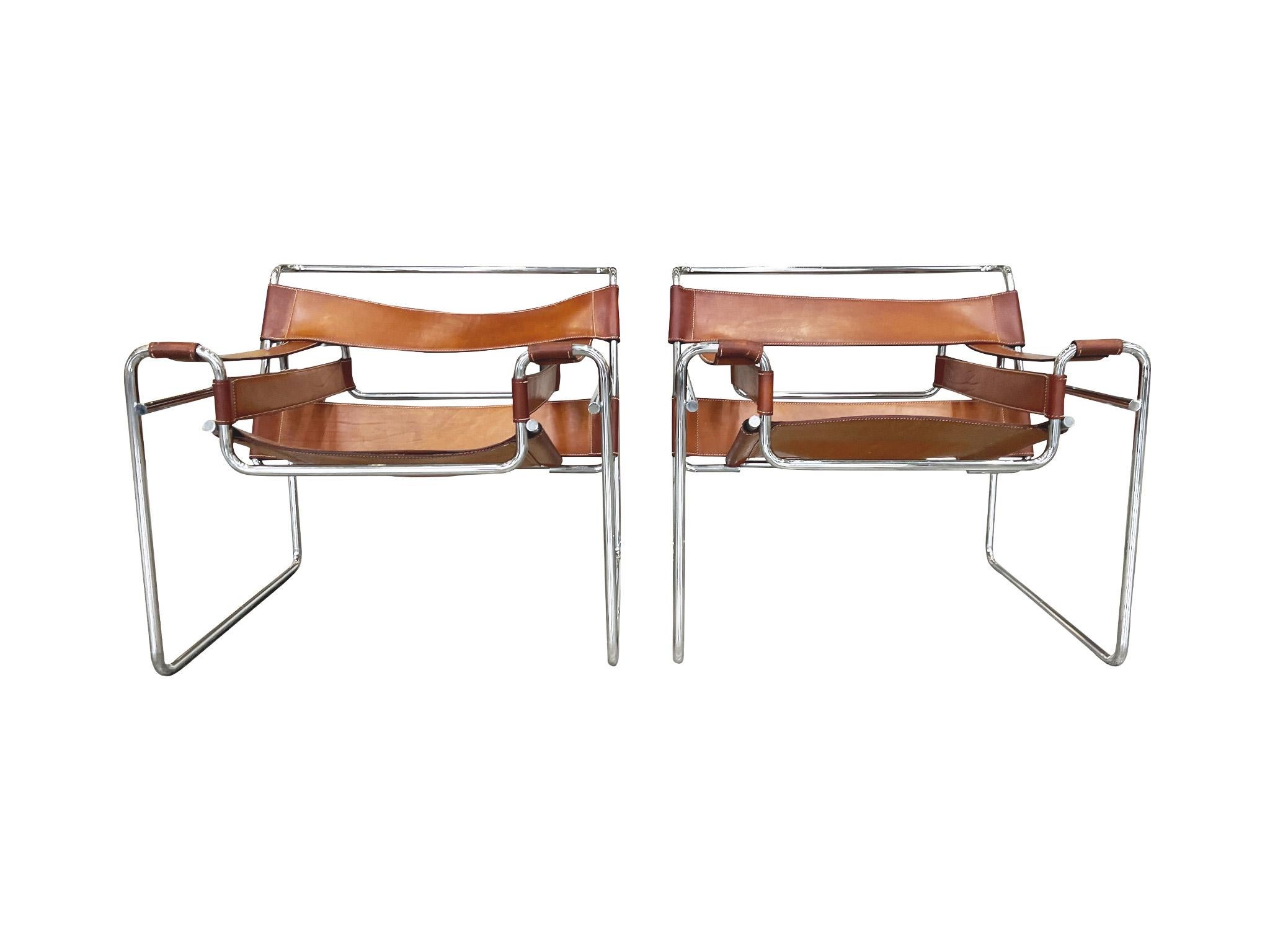 Designed in the 1920s by Marcel Breuer and manufactured in the late 1970s - early 1980s, these iconic Wassily chairs consist of tubular steel frames and leather seating, backing, and armrests. The leather has a rich, burnt-orange