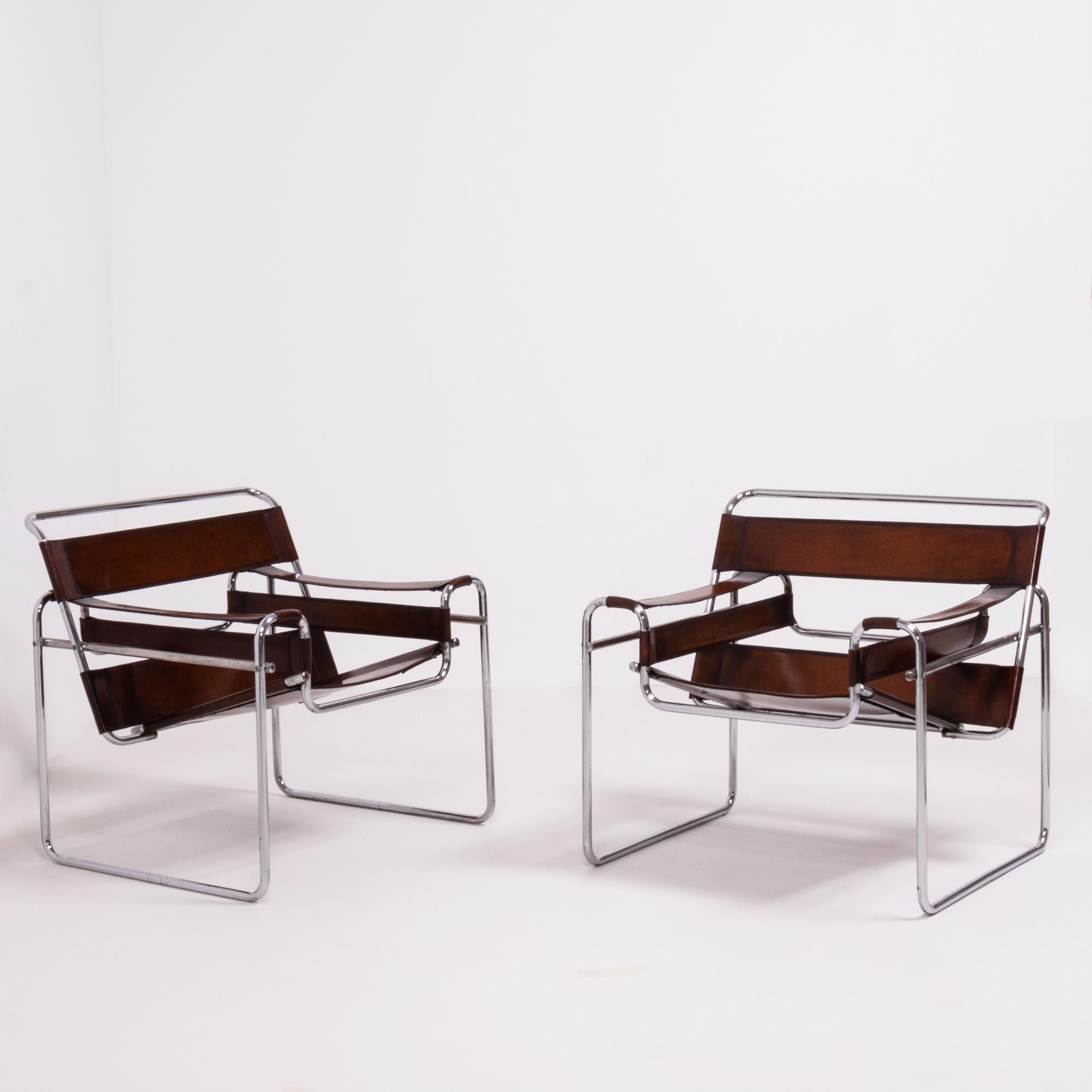 Designed in the style of the iconic Marcel Breuer Wassily, this pair of chairs feature tubular steel frames.

The relaxed angled seats are constructed from a beautiful tan hide with additional panels creating the back and arm rests.
 