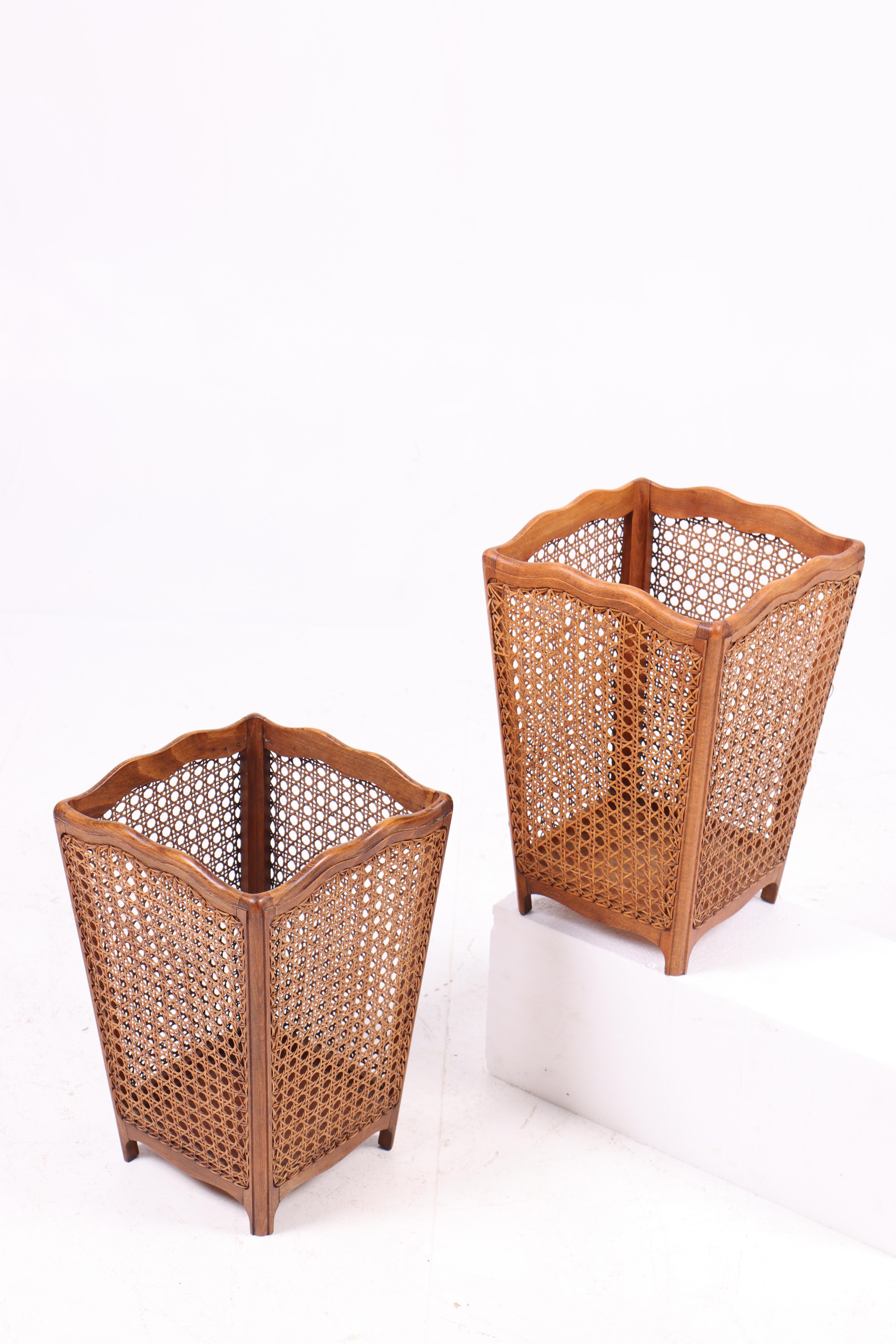 Ces deux poubelles sont en bois de hêtre avec un tissage en canne française et ont été conçues au Danemark dans les années 1950. Leur forme simple et élégante allie la chaleur naturelle du bois de Beeche à l'aspect aérien du motif tissé. Le design