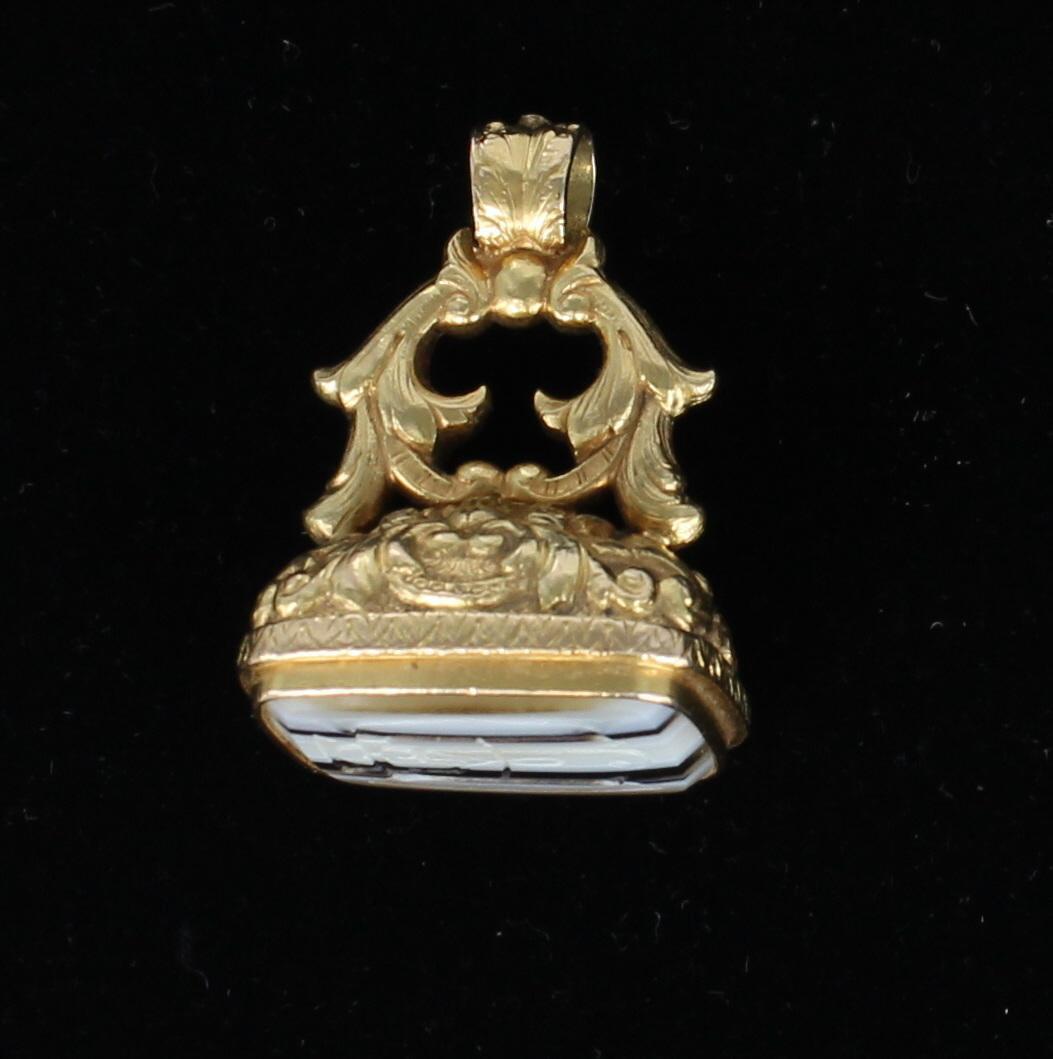 This spectacular Victorian watch fob will turn heads.  The 18 karat yellow gold is magnificently carved to create this exceptional piece from the late 1800's.  The bottom of the fob is set with gorgeous striped agate completing the design of this