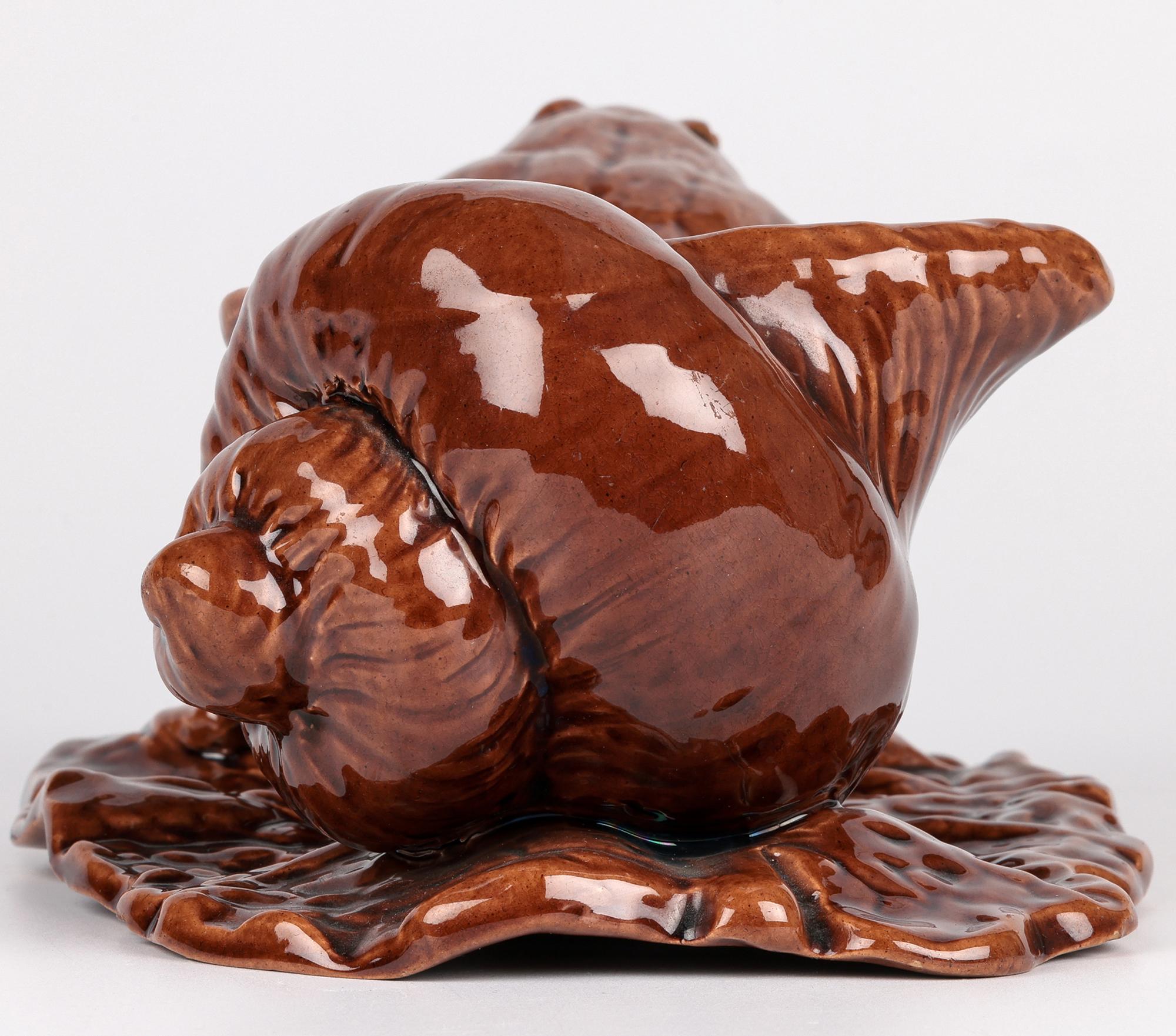 A delightful and scarce Watcombe Torquay Aesthetic Movement art pottery novelty sauce boat modelled as a frog pulling a shell dating between 1880 and 1890. Probably made for Liberty & Co the pottery figure portrays a frog pulling a large shell over