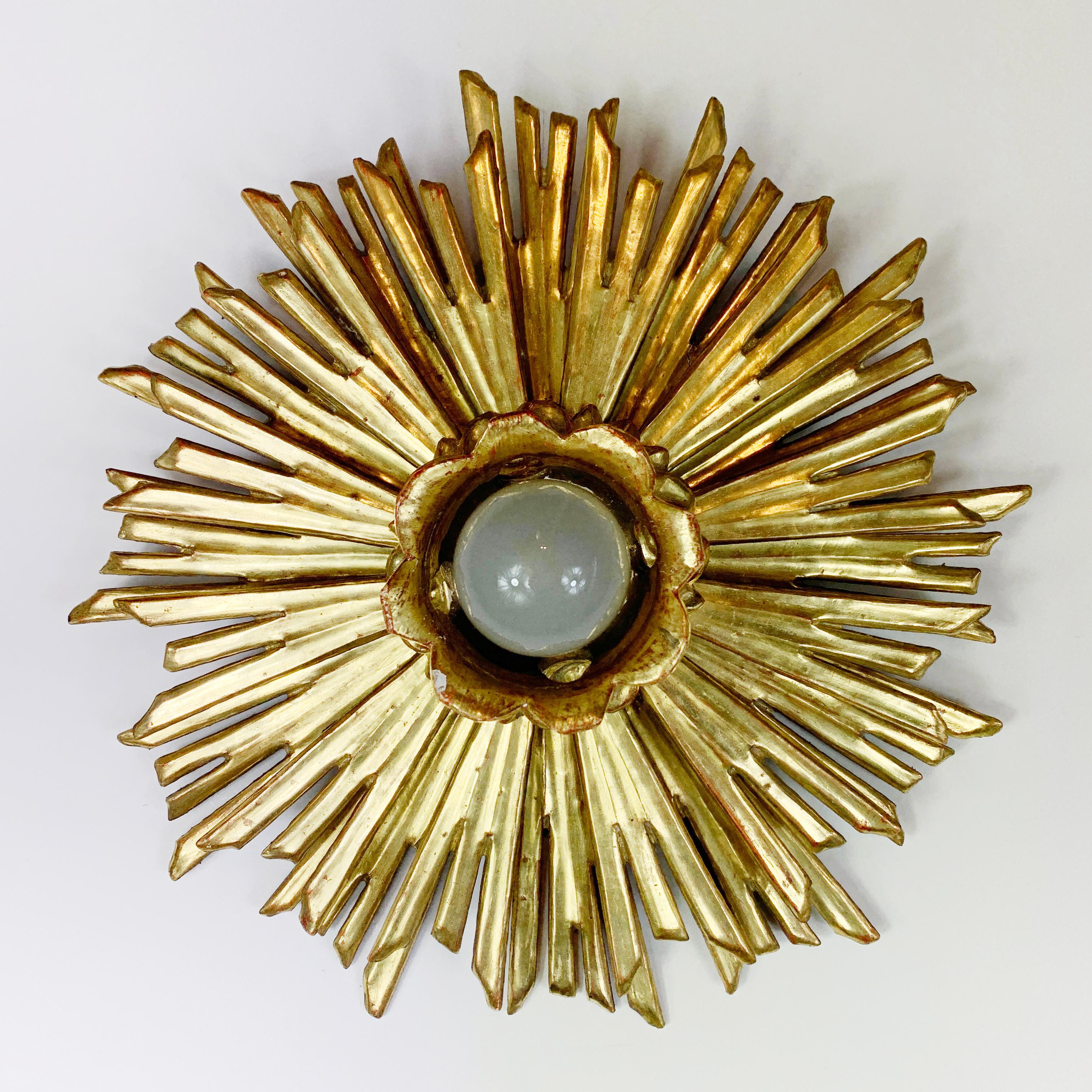 Fabulous 1930's water gilded sunburst flush mount. Carved wooden rays surround the single lamp holder to the centre, originally from a church in Germany this piece is in absolutely glorious condition, the bright gold gilding is superb.

These