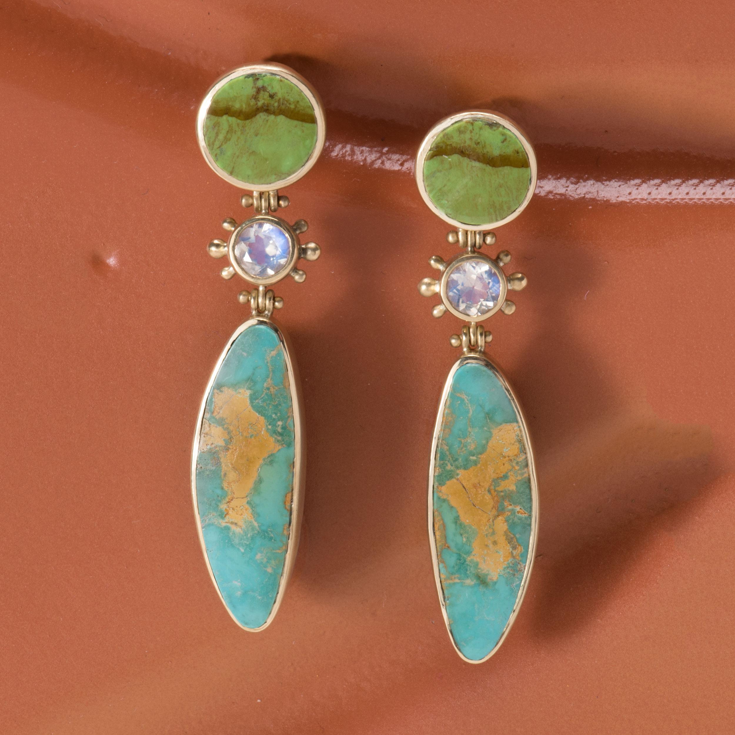 Natural Evans Turquoise from the Nevada mine in blue with an atlas of light rust-colored matrix, drop from faceted moonstones in beaded bezel settings and are topped with disks of Australian Gaspeite with a horizontal pattern of medium brown. These