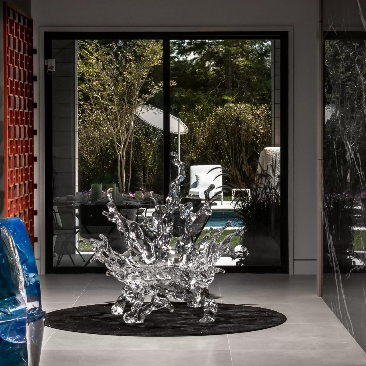 The Water Splash Chaise Lounge captures the essence of fluid motion, inspired by the curves and irregular patterns of splashing water. Crafted from acrylic crystal and featuring the brand's signature embedded leaves, this one-of-a-kind design brings