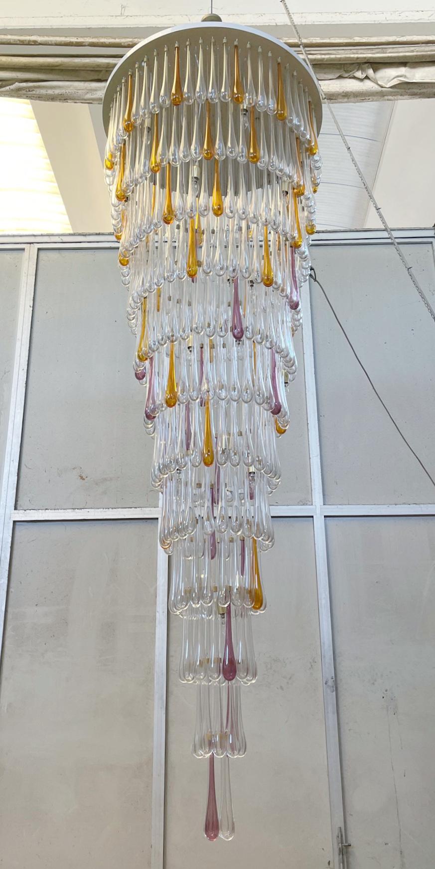 Oversized Italian chandelier shown in 12 tiers of hand blown Murano hollow glass drops in clear mixed with orange and amethyst colors, hanging from glossy white ceiling plate / Made in Italy
24 lights / E12 or E14 type / max 40W each
Measures: