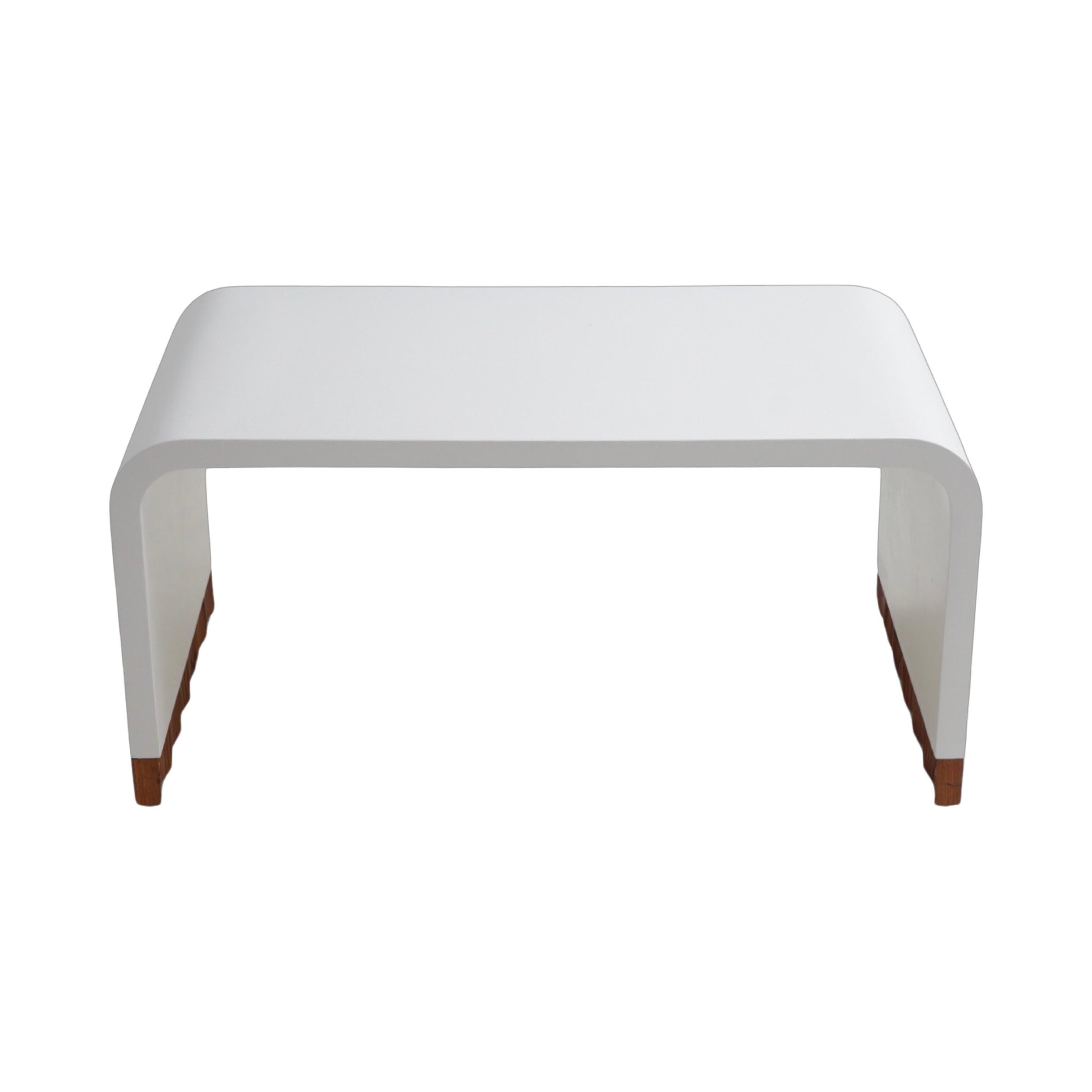 Slick, sleek, and dazzling in white, this waterfall coffee table may mesmerize you with its curves and blind you with its striking beauty. The wood zig-zag base of the table adds a quirky flair to a classic design that your coolest interior design